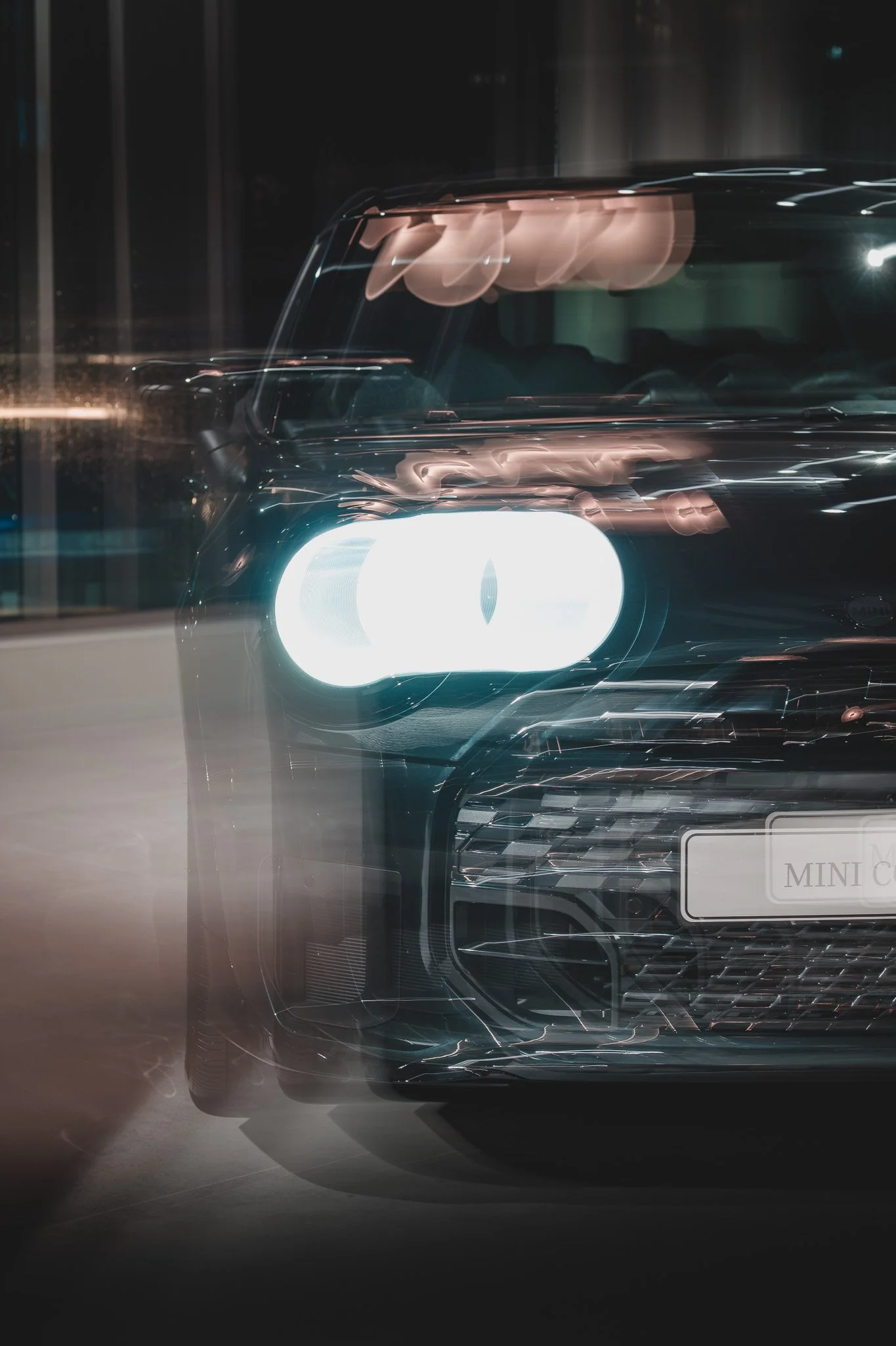 Voiture noire avec phares allumés dans une ambiance nocturne, avec un effet de mouvement flou.