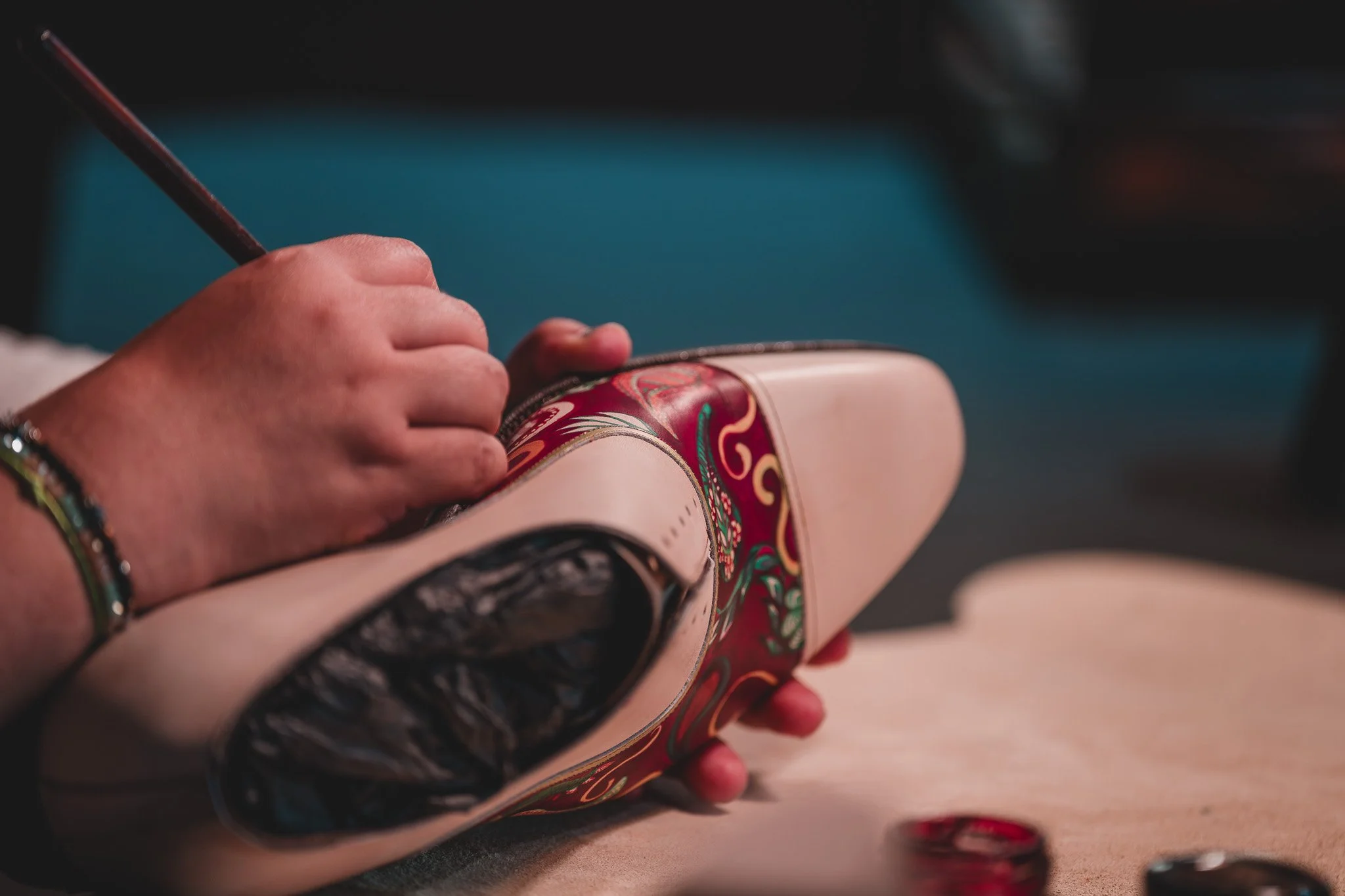 Une personne qui peint une chaussure avec des motifs colorés.