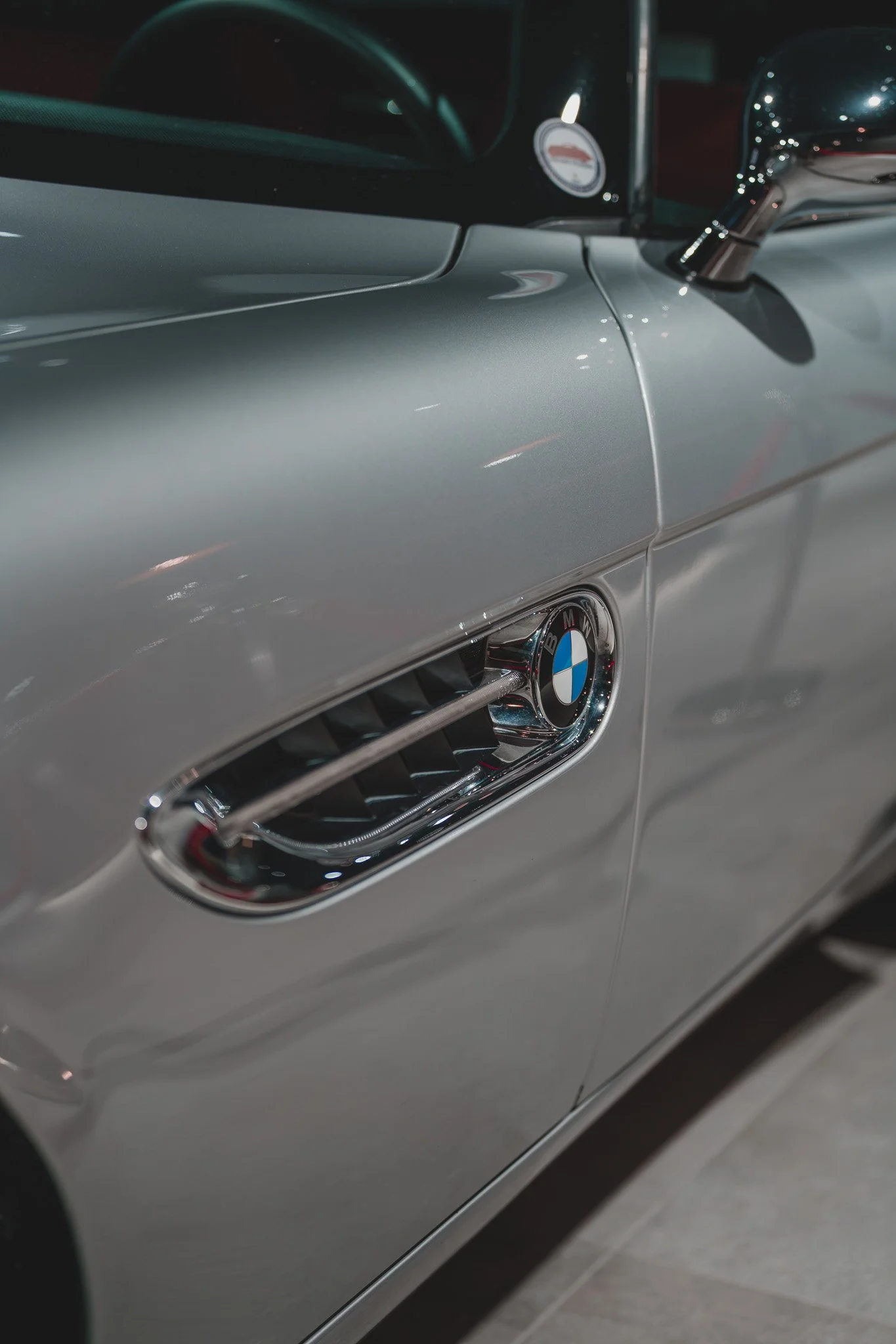 Détail d'une voiture BMW de couleur argentée avec une entrée d'air sur le côté.