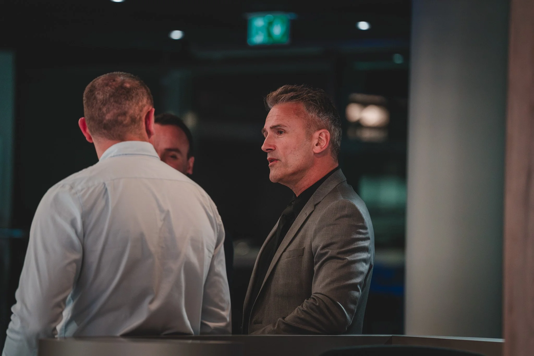 Trois hommes d'affaires en discussion dans un espace intérieur moderne.