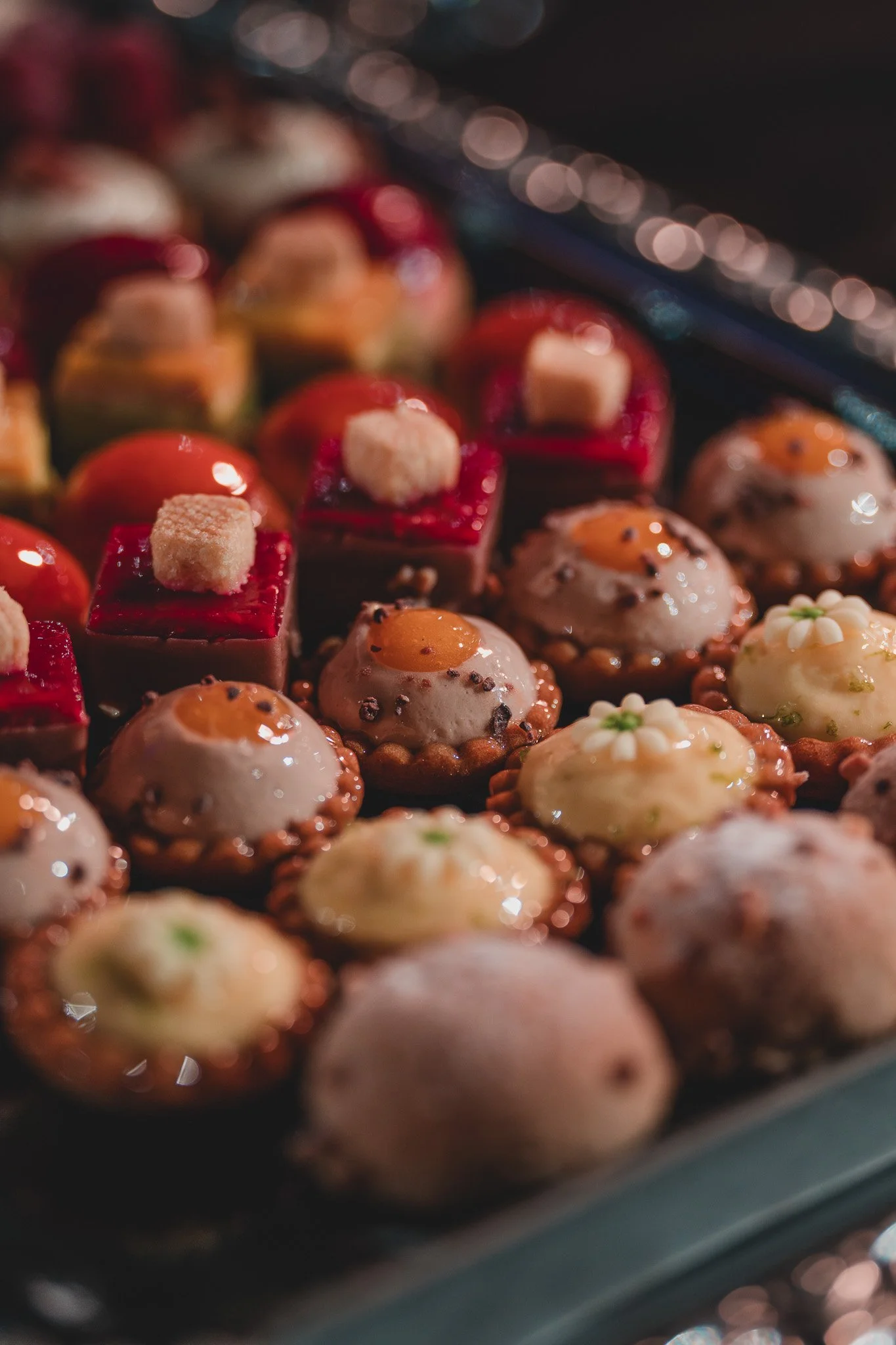 Une variété de petits desserts délicats, dont des tartes avec crème et garniture, sur une plaque de cuisson