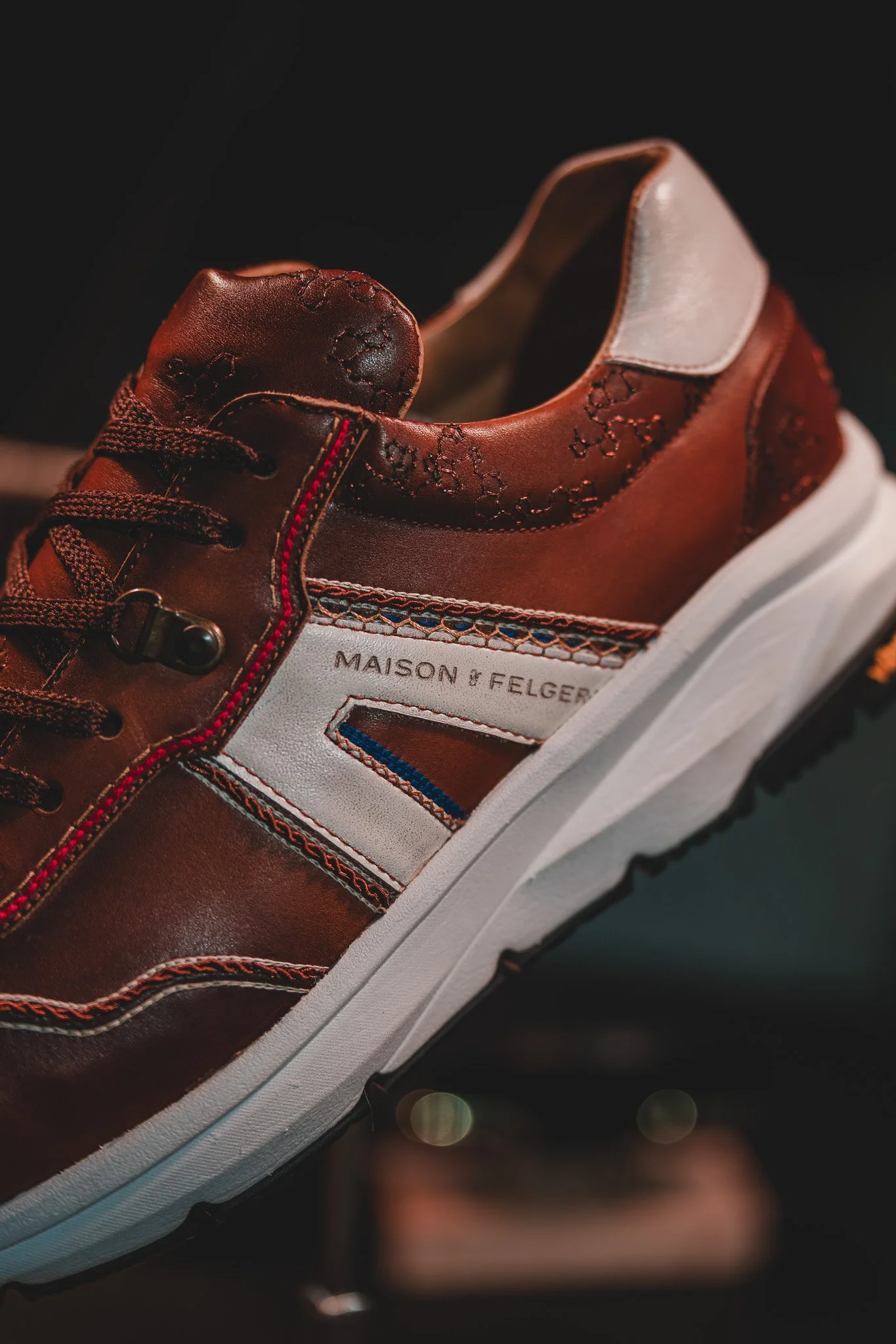 Chaussure de sport en cuir marron avec détails en blanc, bleu et rouge, portant la marque 'Maison & Felger'.