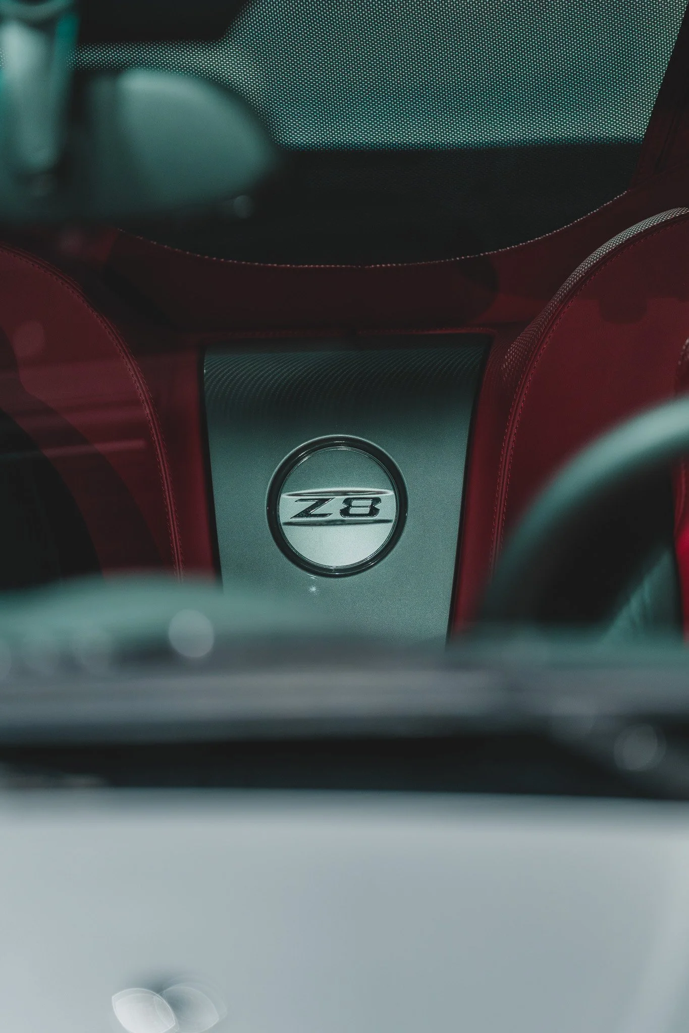 Intérieur d'une voiture de luxe avec un badge 'Z8' au centre de la console, sièges en cuir rouge.