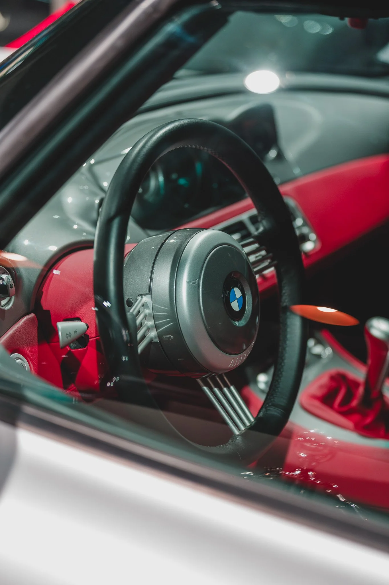 Intérieur d'une voiture de sport BMW avec volant noir, tableau de bord rouge et levier de vitesse rouge