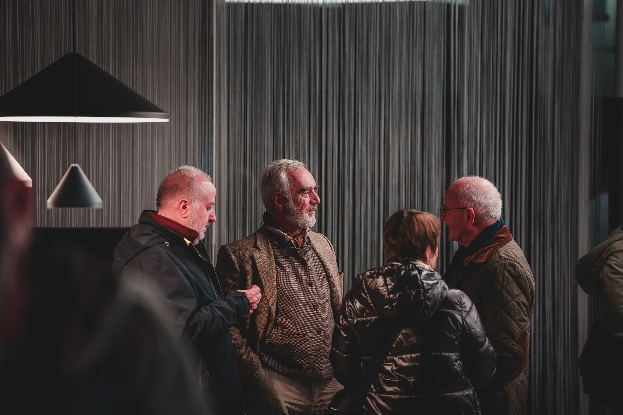 Groupe de quatre personnes âgées discutant dans un espace intérieur moderne.