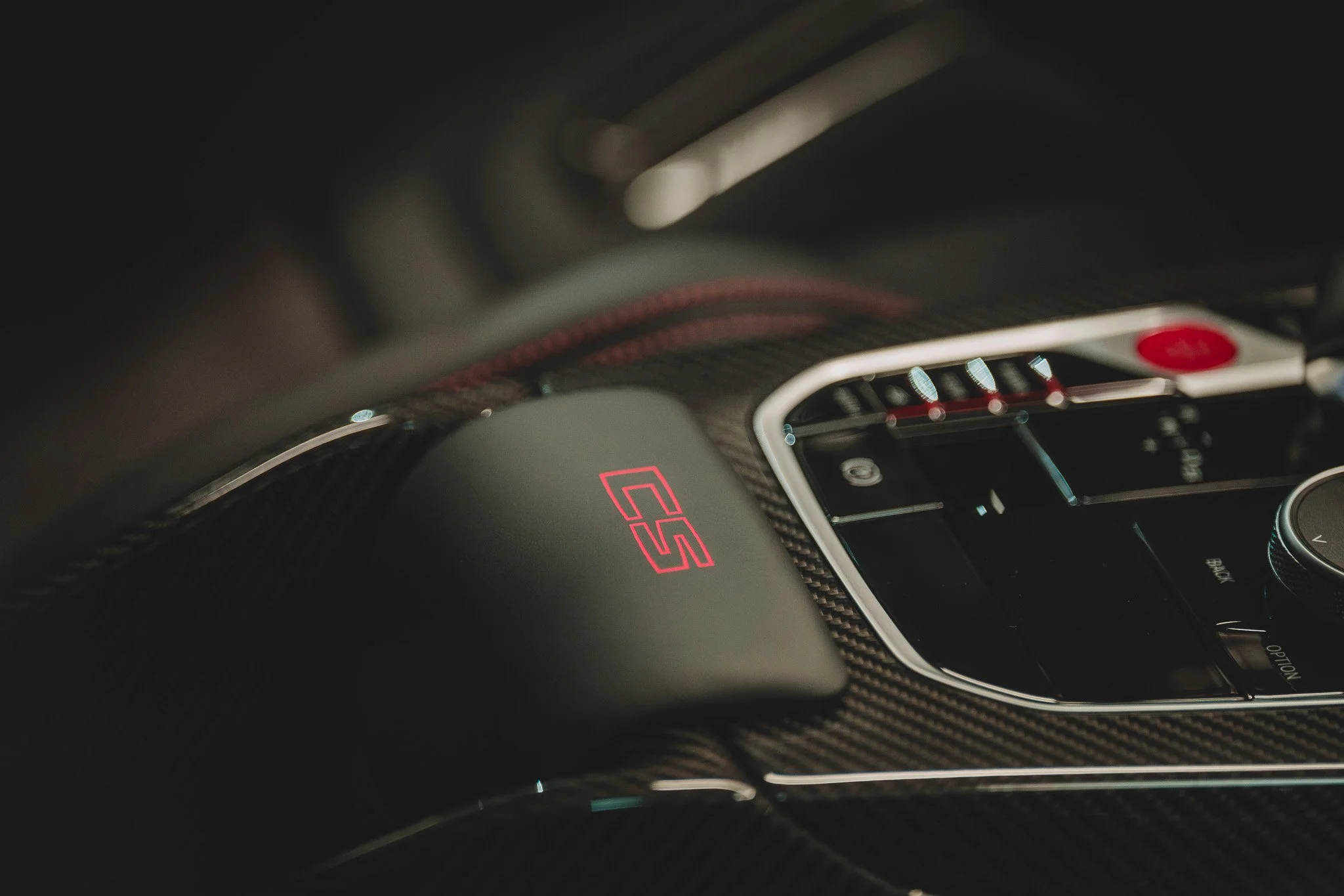 Le tableau de bord intérieur d'une voiture sportive, mettant en évidence le logo 'GTS' en rouge sur le tableau de bord et des éléments de contrôle en noir et argent.