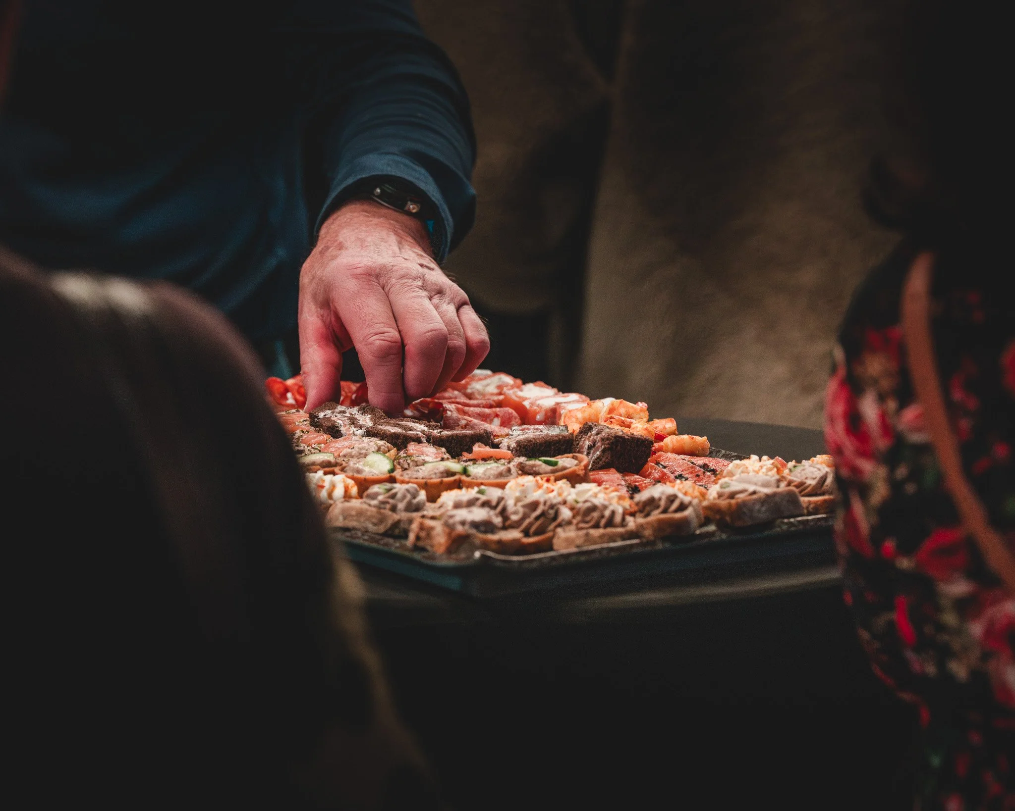 Main qui sélectionne des amuse-gueules sur un plateau.