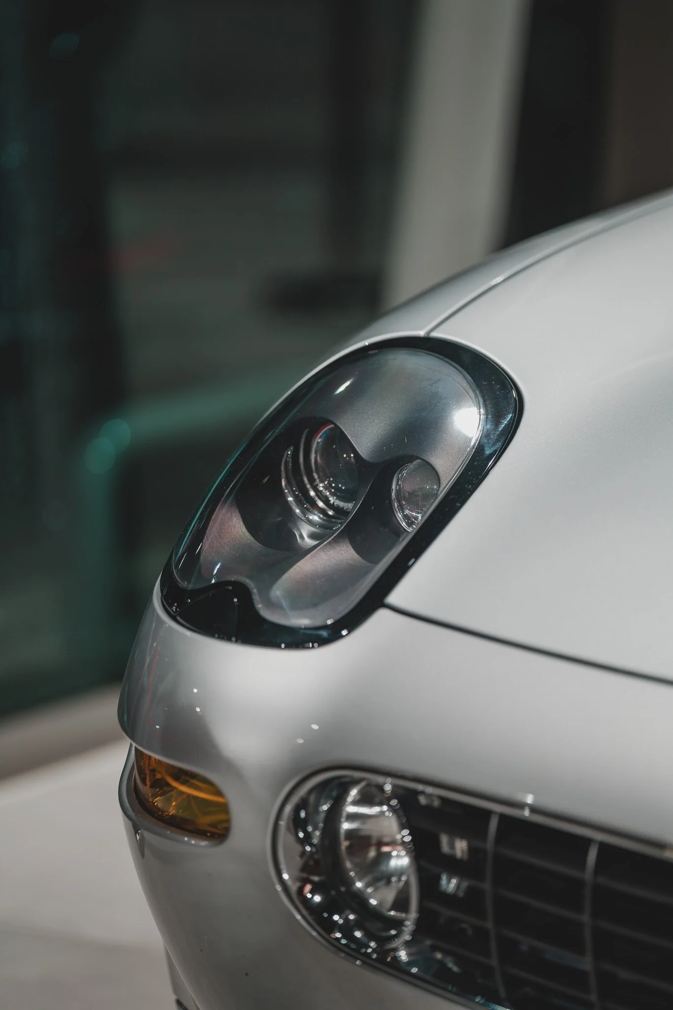Prise en gros de la partie avant d'une voiture blanche, mettant en évidence le phare, la calandre et une lampe orange d'indicateur.