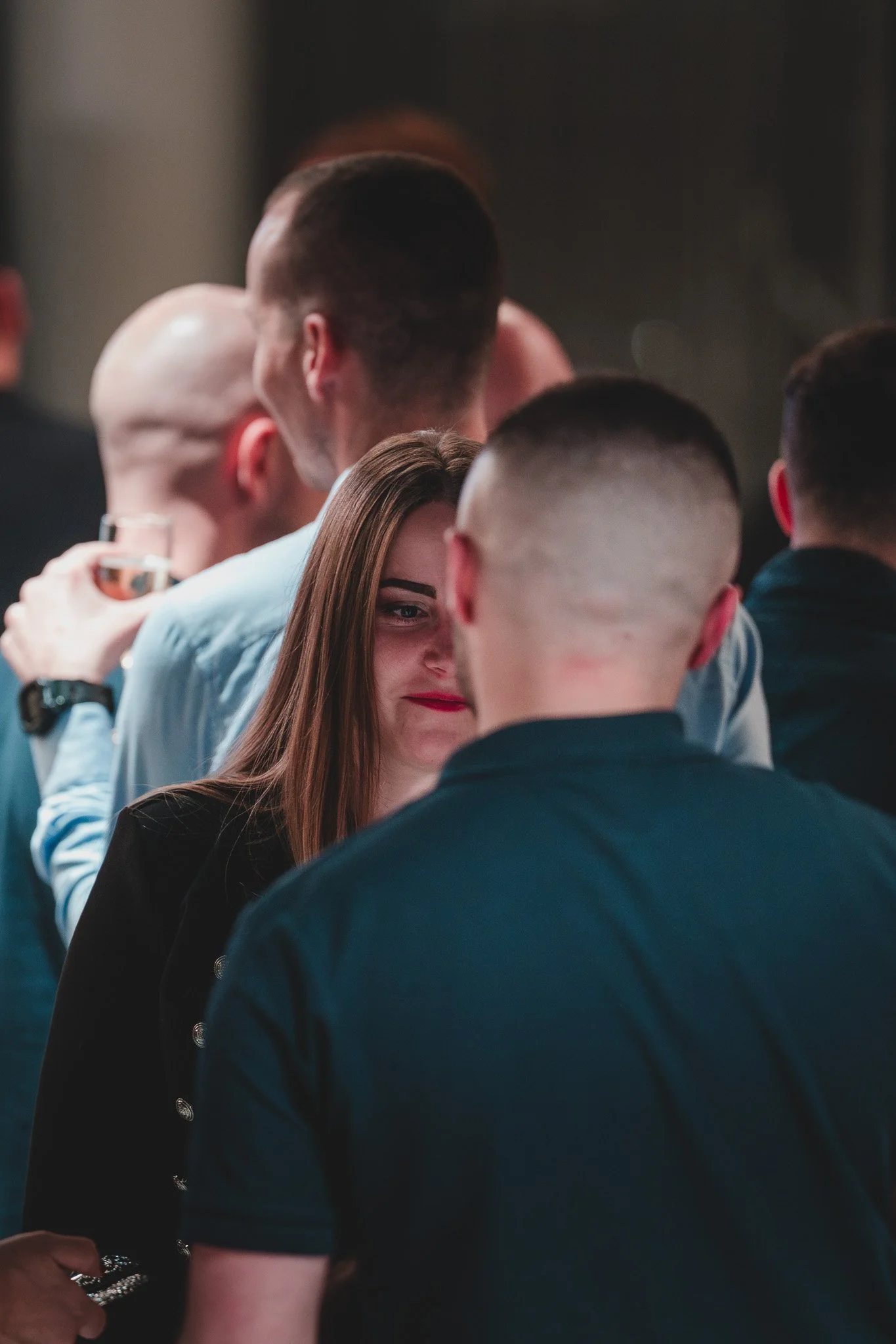 Un groupe de personnes en tenue décontractée ou de soirée, se tenant en ligne et échangeant des conversations ou des salutations, lors d’une réunion ou d’un événement social.