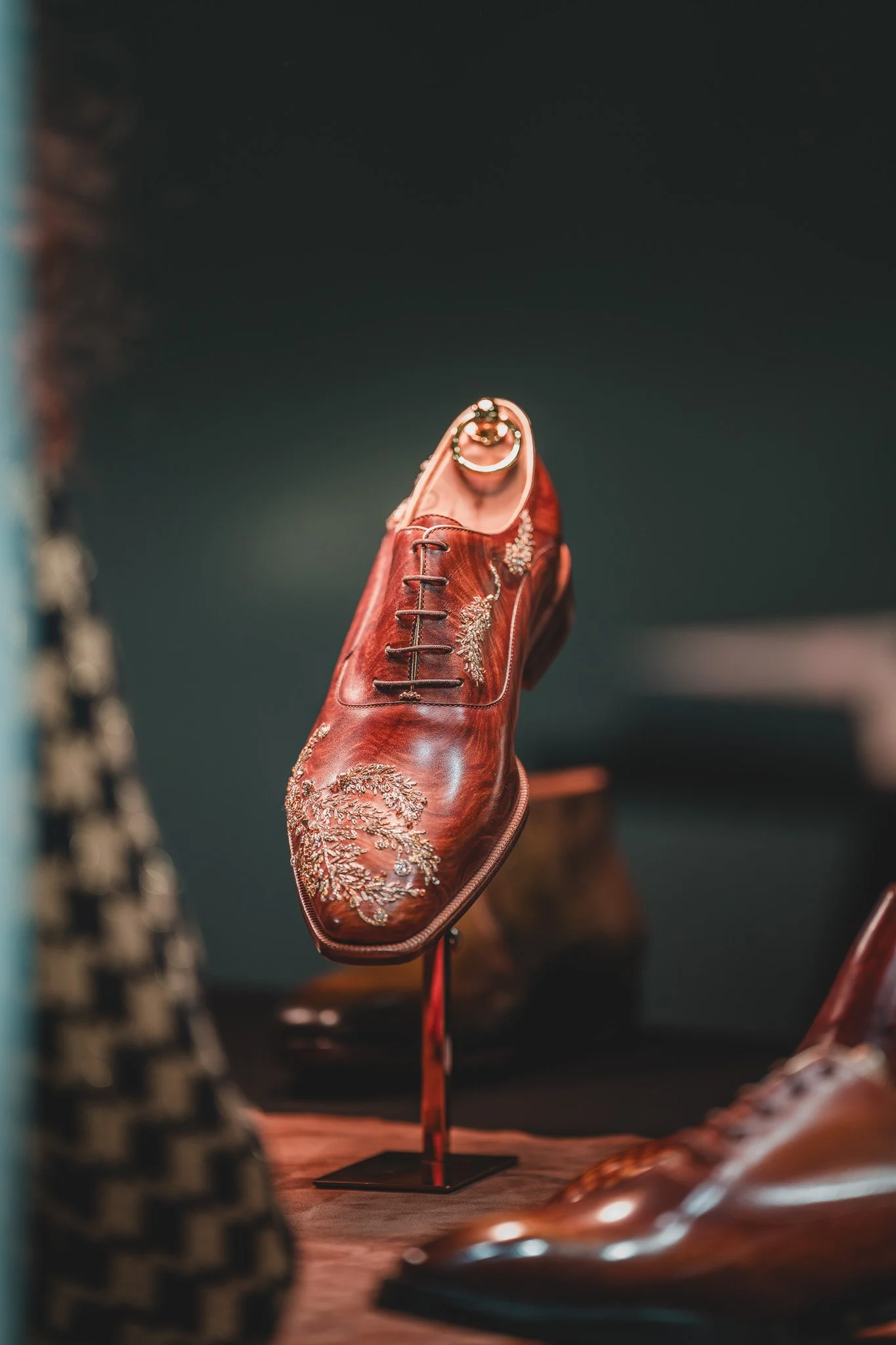 Une chaussure en cuir marron ornée de broderies dorées, exposée en tant qu'objet decoratif ou lors d'une exposition.