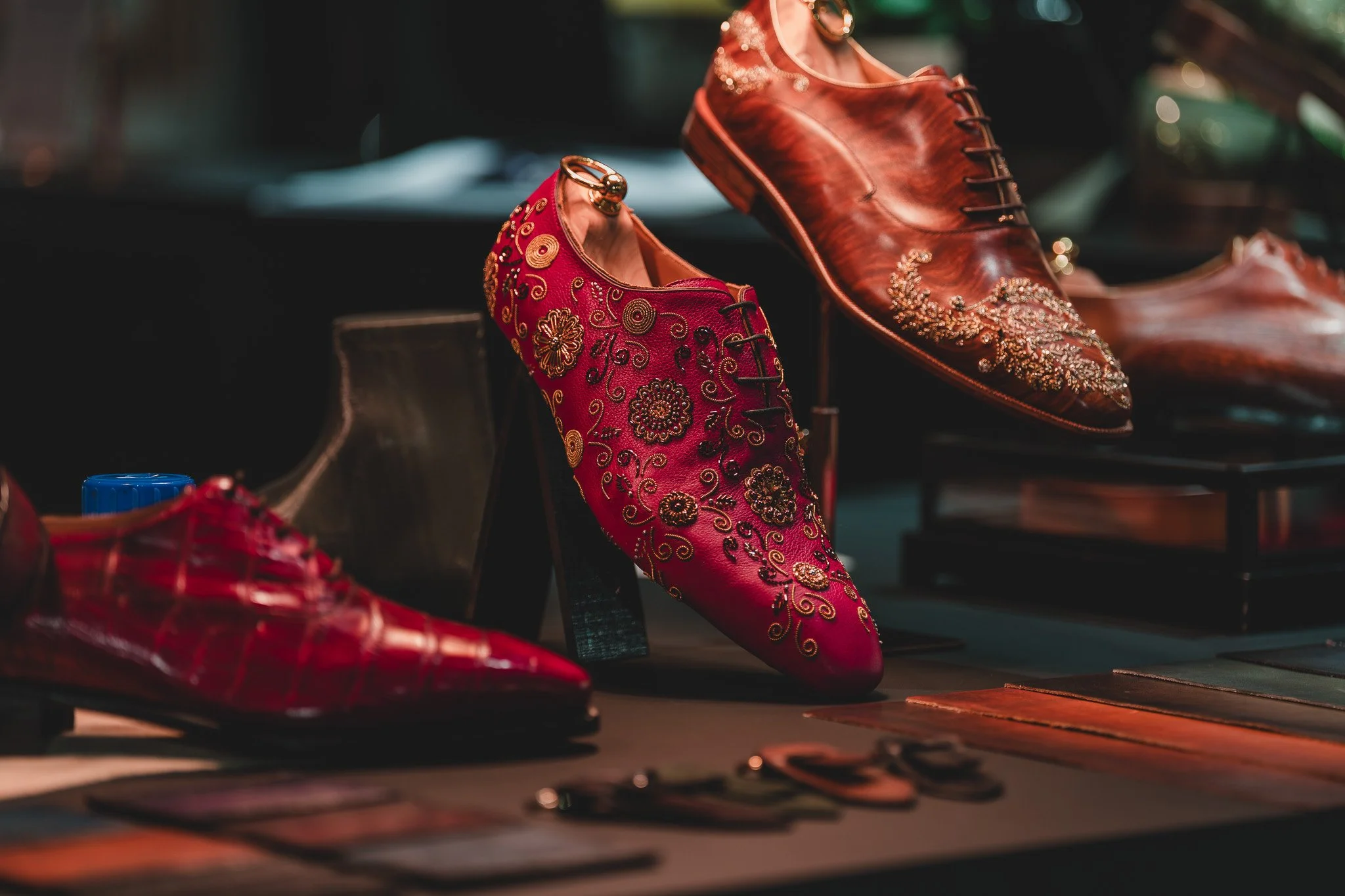 Chaussures en cuir et en tissu avec des broderies et des embellissements, exposées en vitrine.