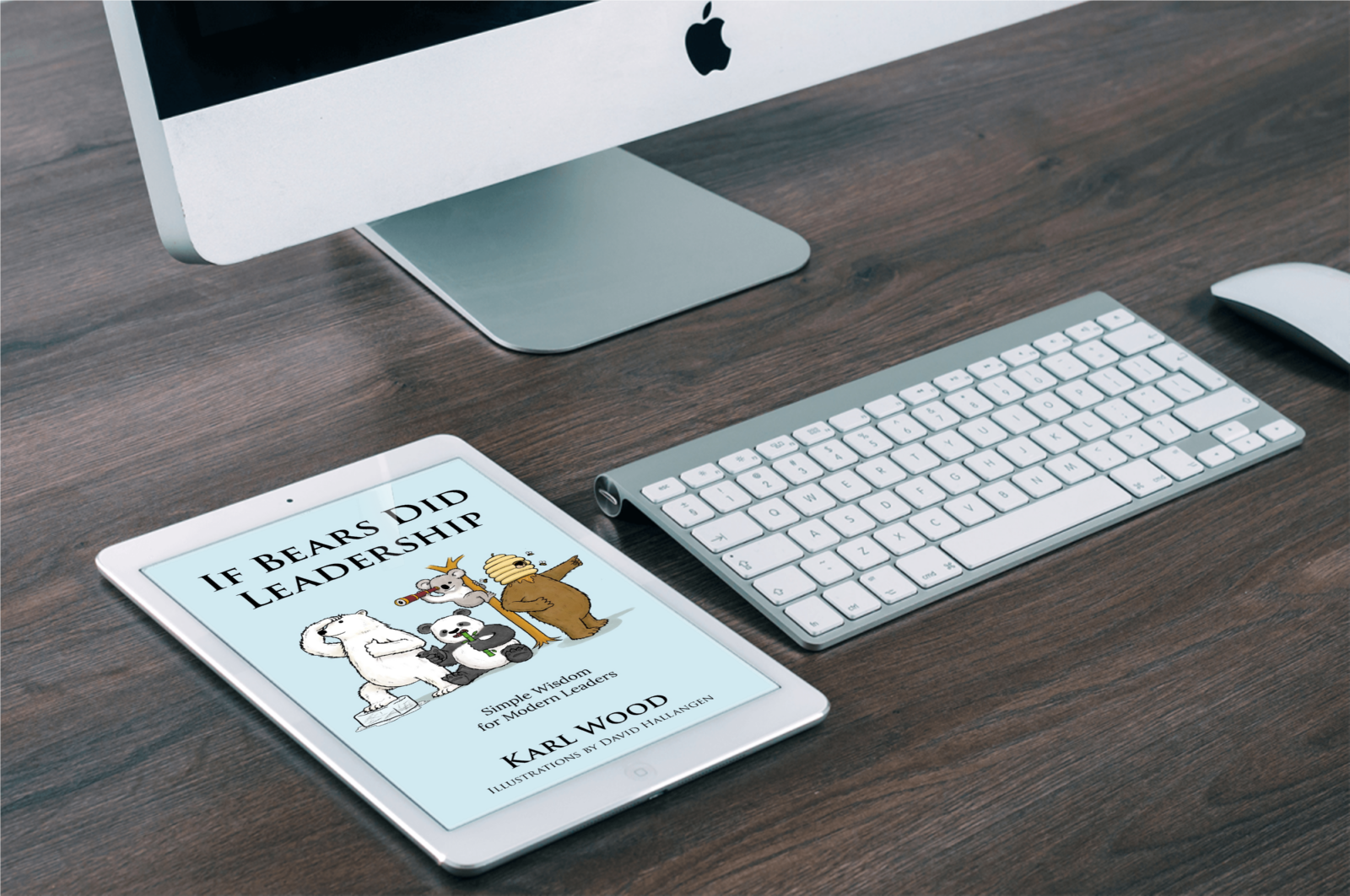 A white tablet displaying the cover of a book titled "If Bears Did Leadership" with cartoon bear characters, a white Apple desktop monitor, a white wireless keyboard, and a white mouse on a wooden desk. Written by author Karl Wood, HR Consultant.