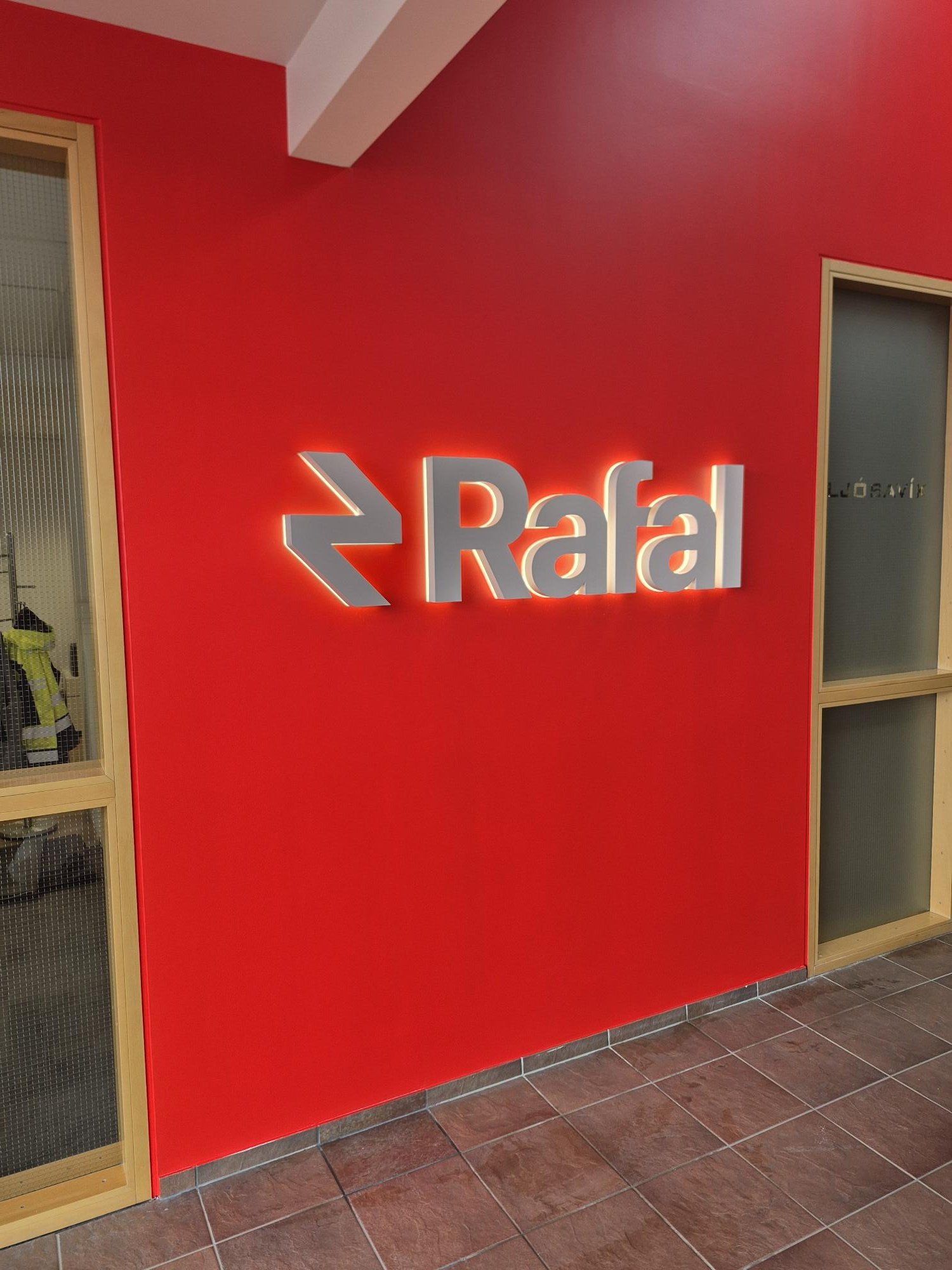 Sniðmát og raflagnir á rauðum vegg fyrir uppsetningu á baklýstum stöfum og merki Rafal.