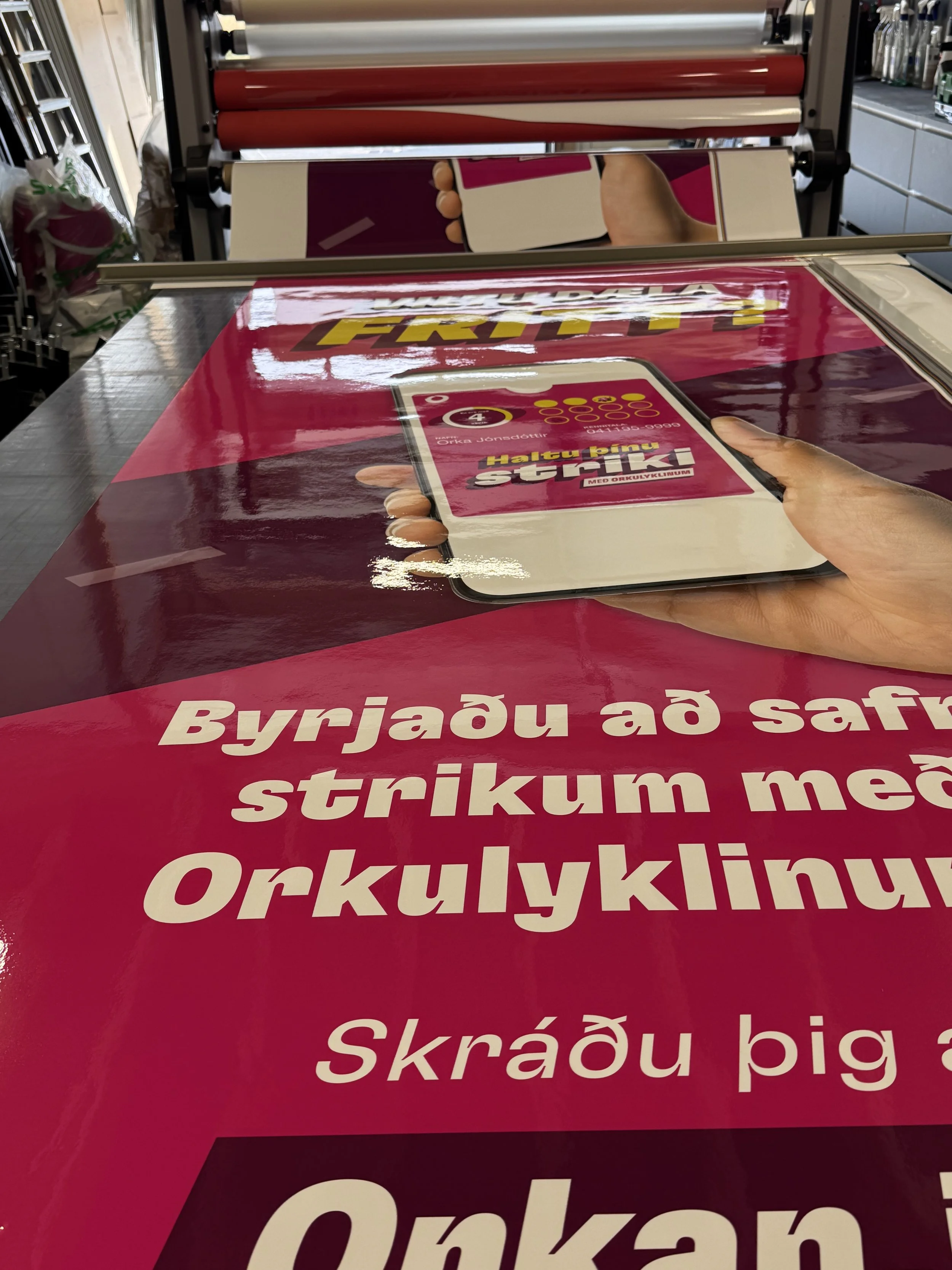 Nærmynd af herferðarskilti fyrir Orkan með bleikri grafík og auglýsingu í ramma.