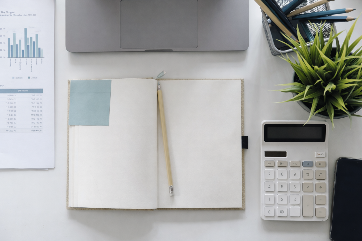 Schreibtisch mit Notebook, Notizbuch, Bleistift, Papiere, Pflanzen, Taschenrechner, Stiftbehälter mit Stiften und Papier, Tablet.