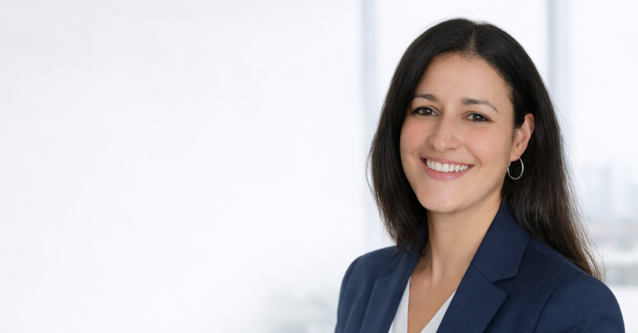 Lächelnde Frau in blauer Anzug vor einem Fenster mit Stadtblick.