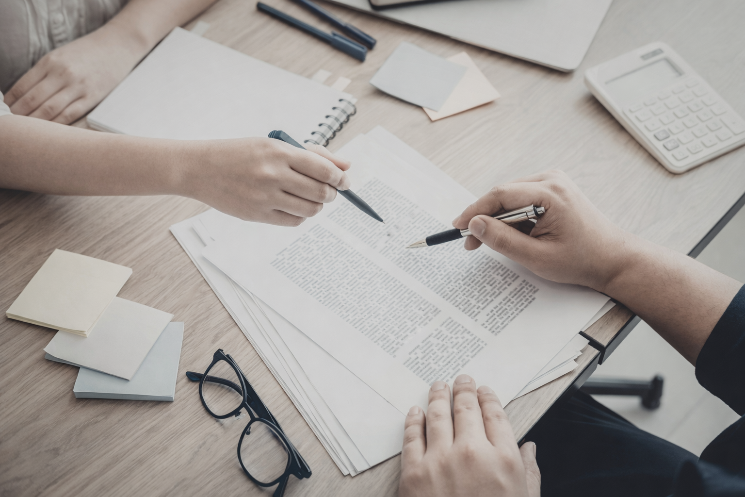 Ein Mann sitzt nachdenklich auf einer Bank in einem hellen Raum, trägt ein braunes Polo-Shirt und weiße Hosen.
