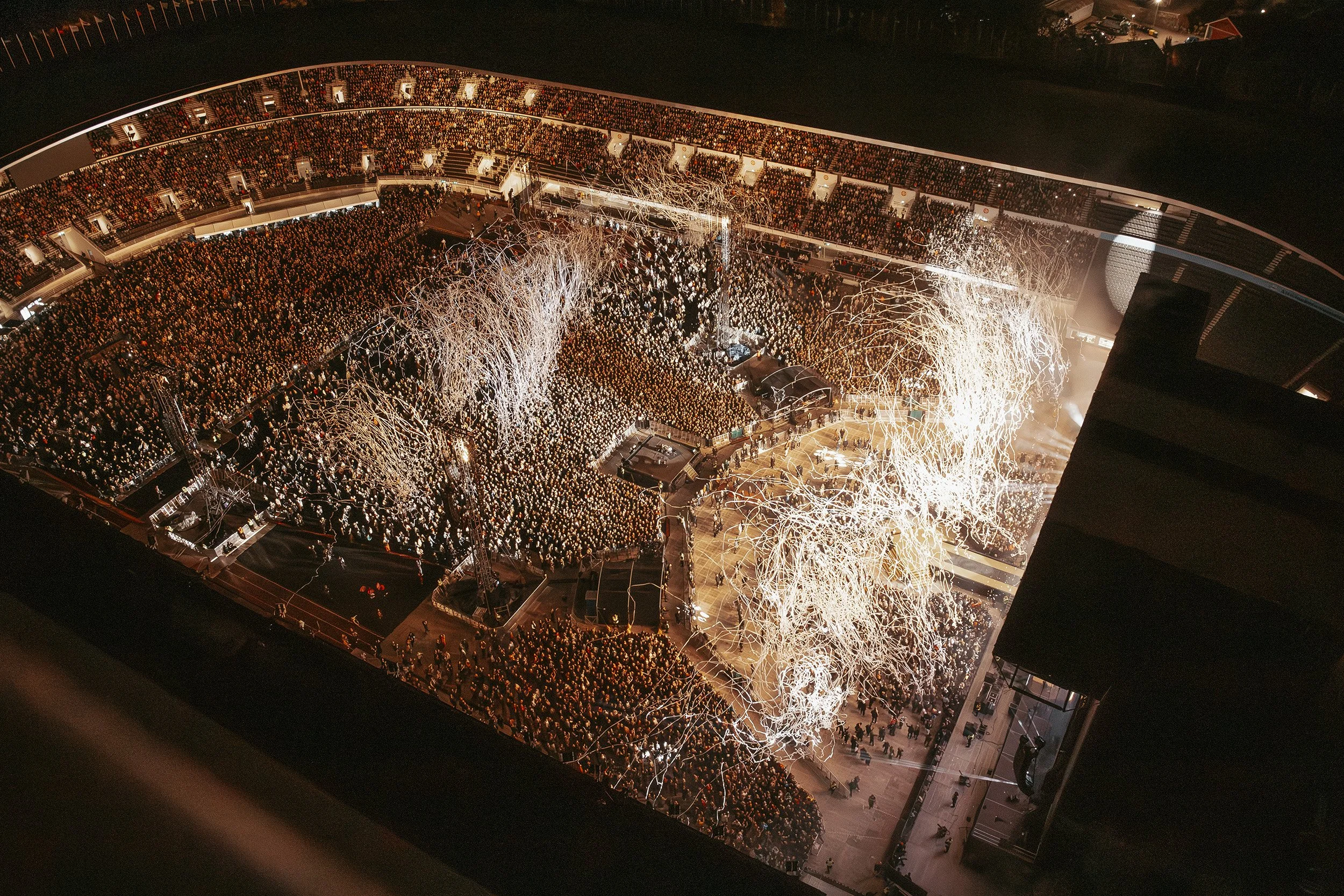 Ilotulitteita ja suuri ihmisjoukko stadionilla yöllä.
