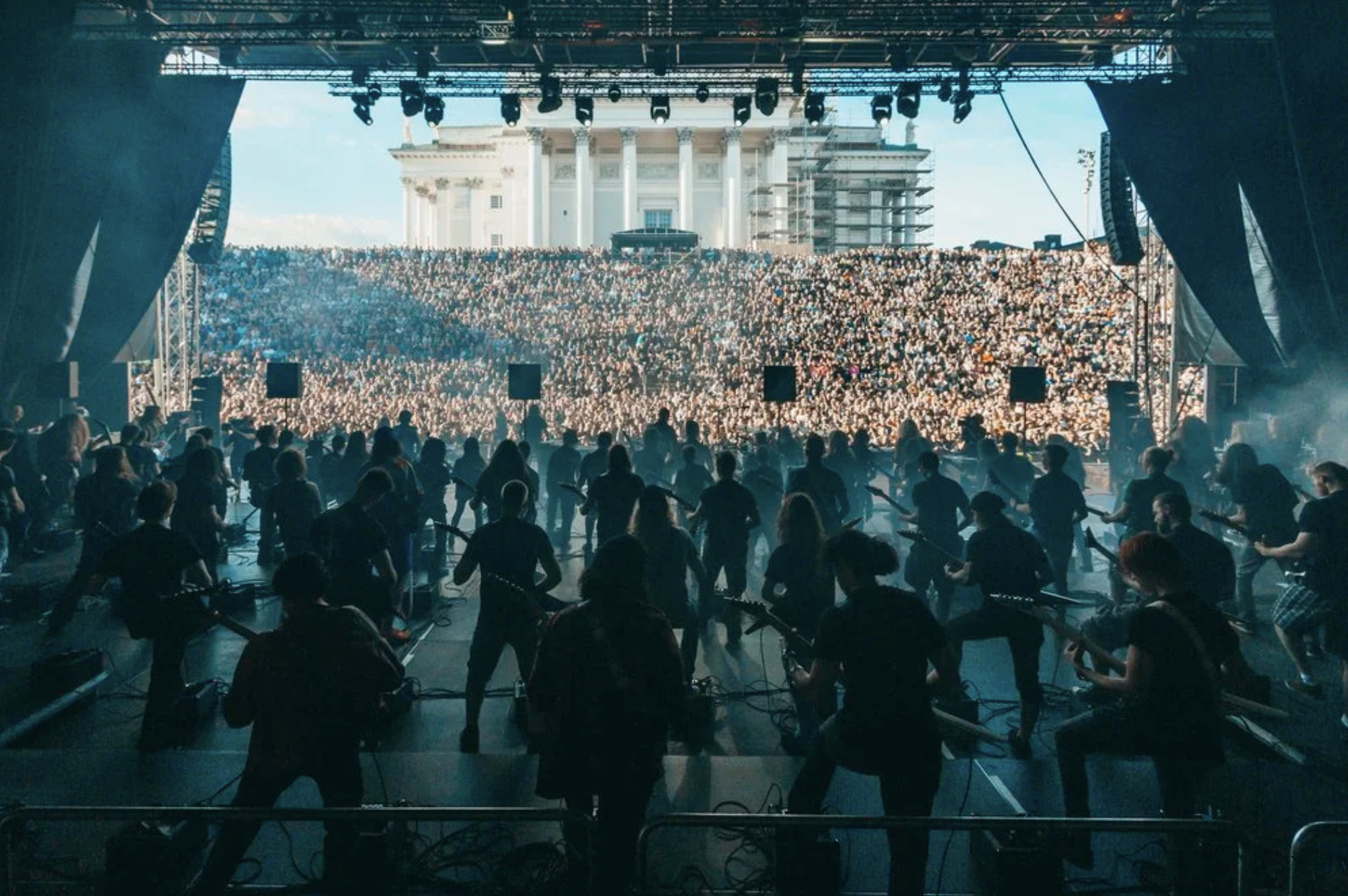 Konsertti ja suuri yleisö katsomassa esiintyjiä jotka soittavat ja tanssivat lavalla, taustalla suuri kirkko ja rakennus.