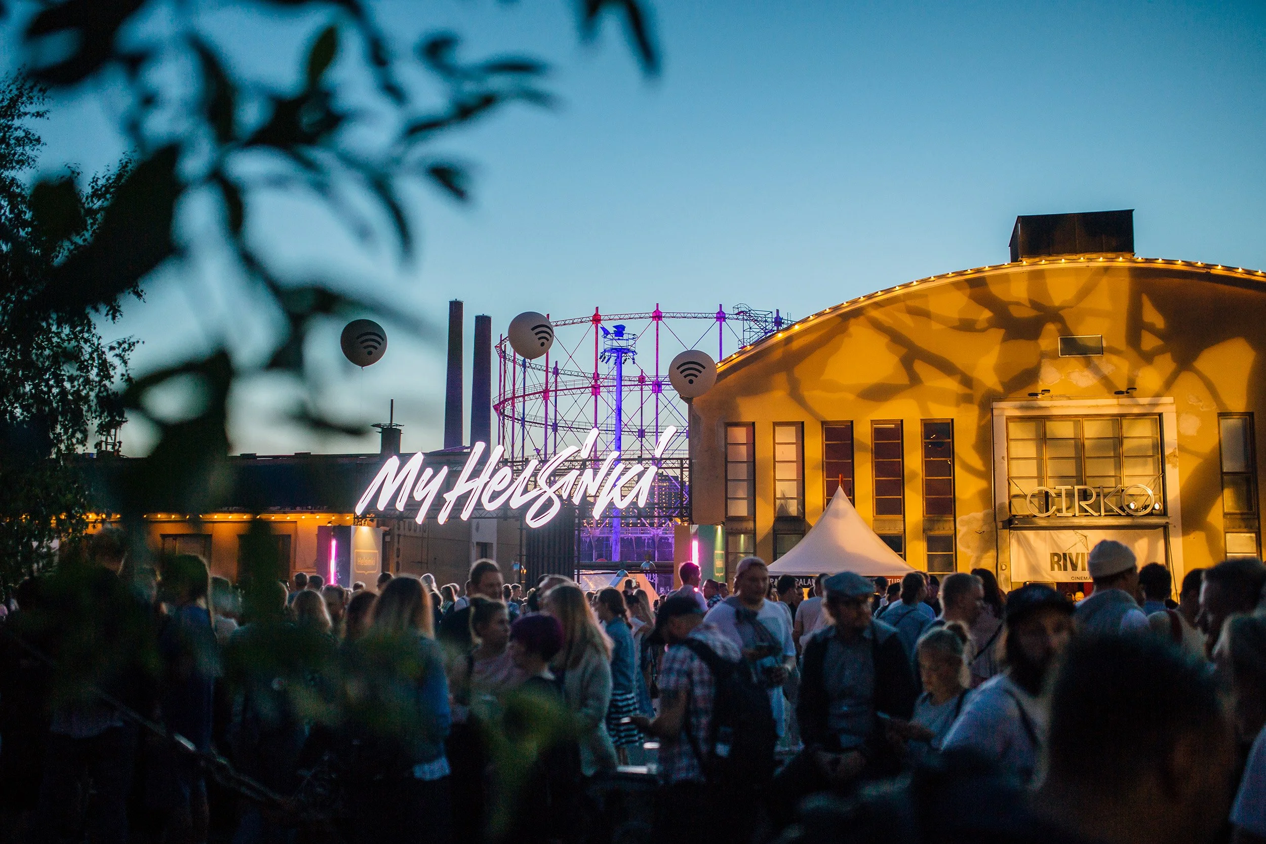 Tapahtuma Helsingissä, suuri ihmisjoukko illassa, valotehosteita ja rakennuksia, joissa on kirjaimet My Helsinki ja Cirko, taustalla rakenteita ja valoja.