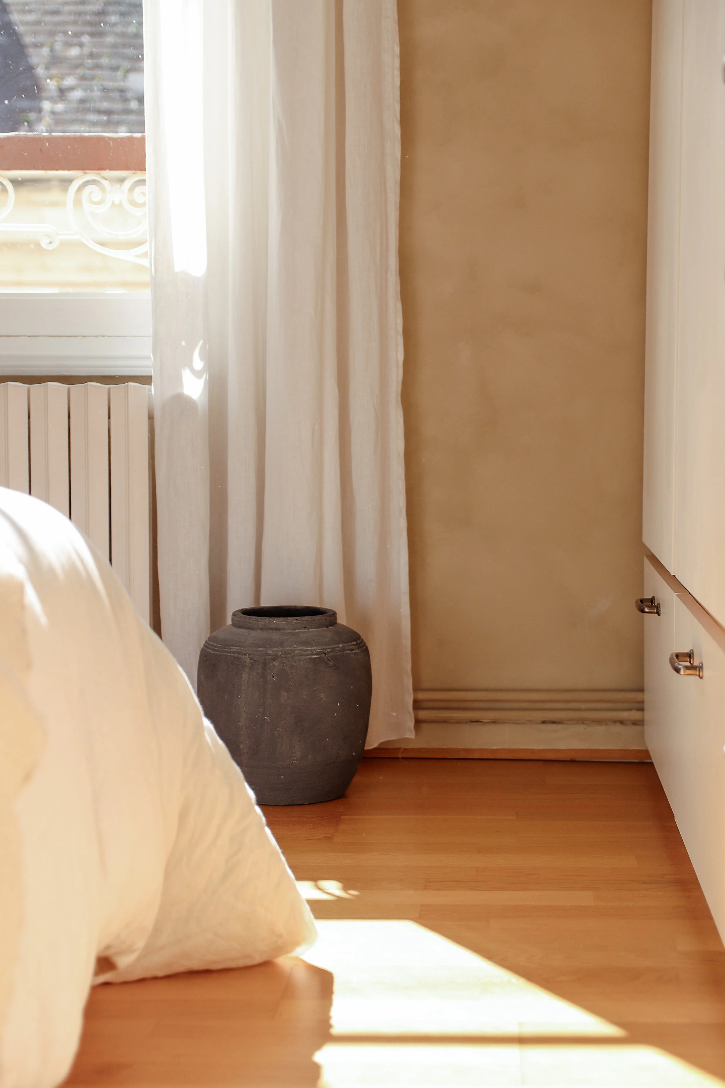 Détail chambre parentale avec mur à la chaux beige ressource, parquet, draps en lin