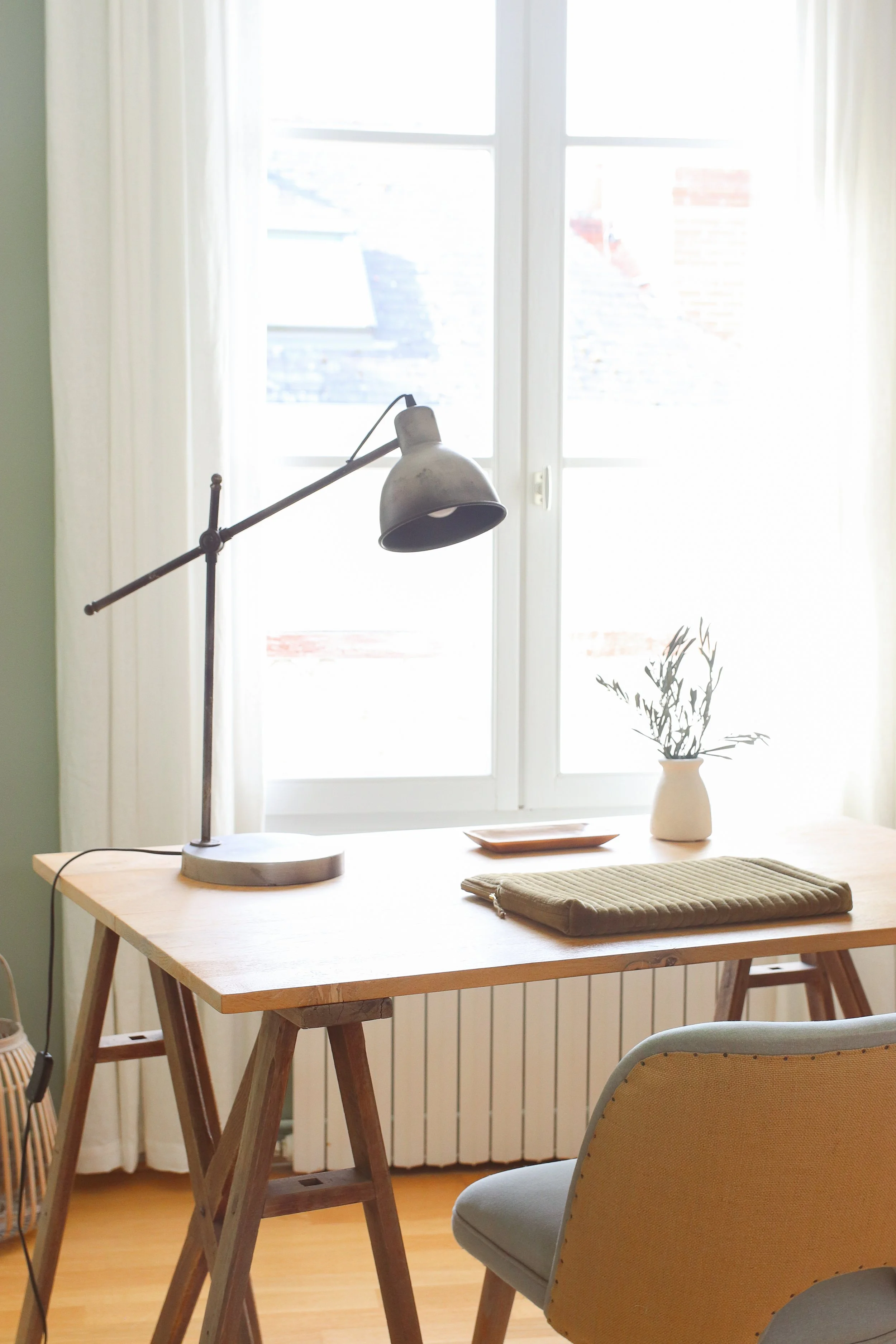 Bureau en bois avec tréteaux bois, lampe architecte et fauteuil en lin et jute
