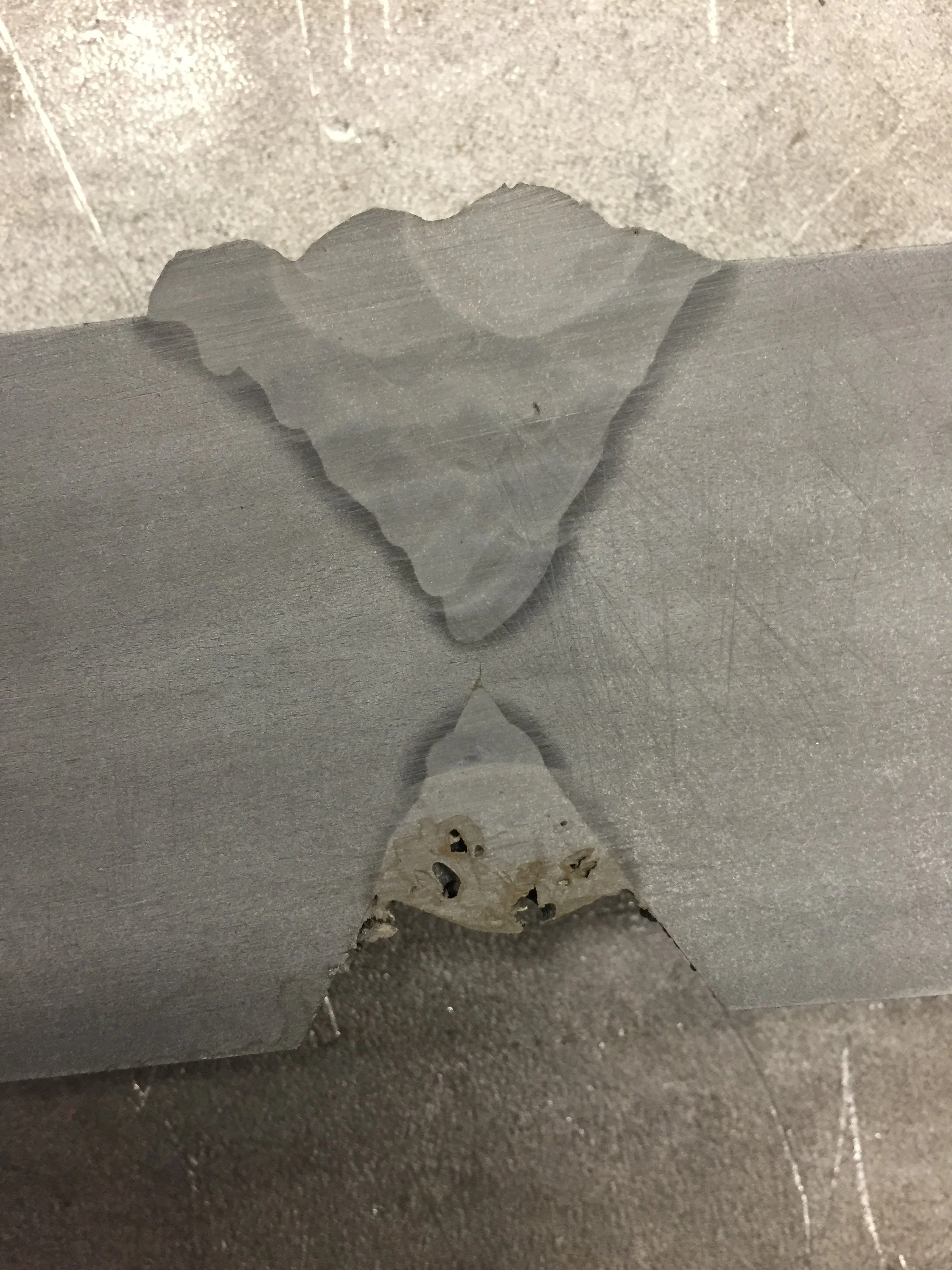 Dried glue and peeling tape on a light gray surface with a textured floor in the background.