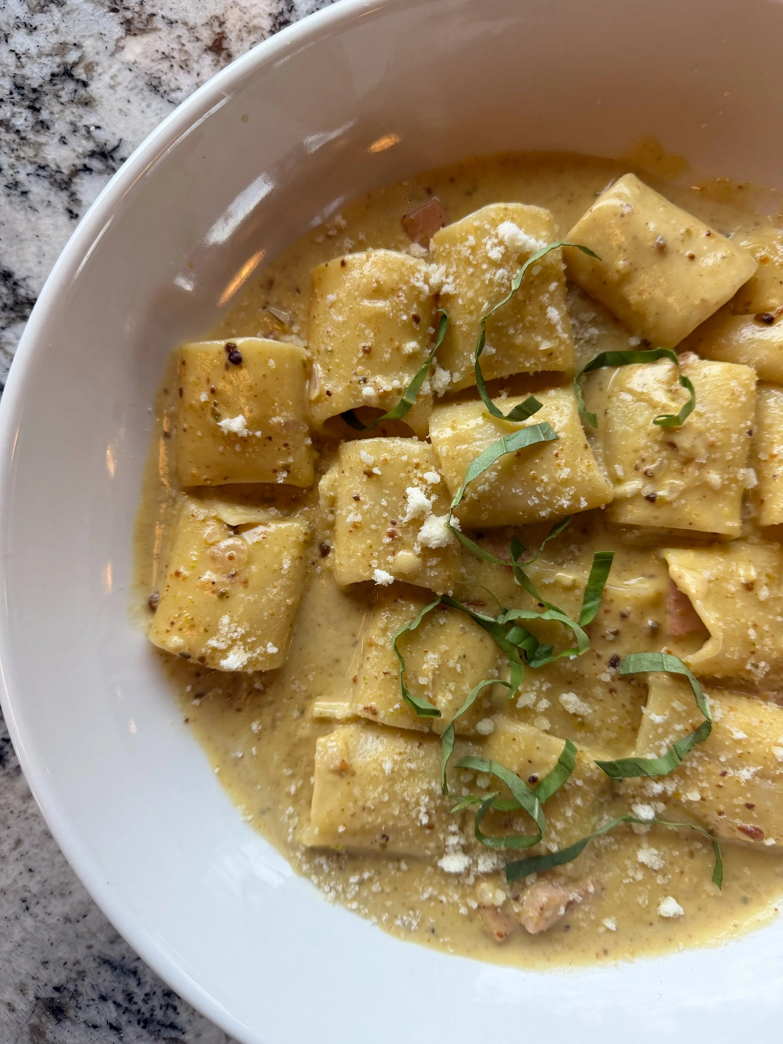 A bowl of pumpkin gnocchi with sage, grated cheese, and black pepper.