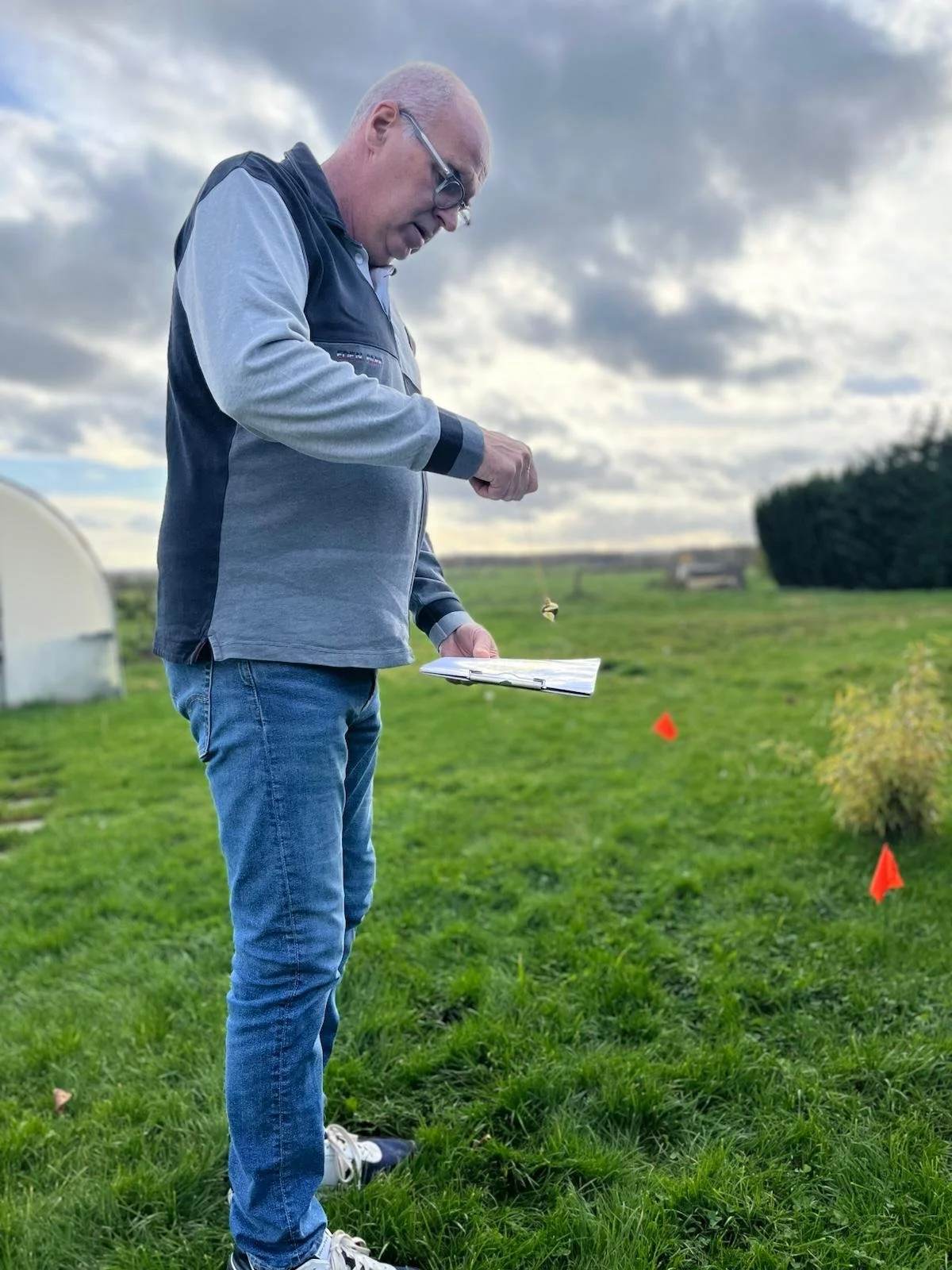 Un homme regarde tient dans ses mains des baguettes de sourcier dans un champ vert