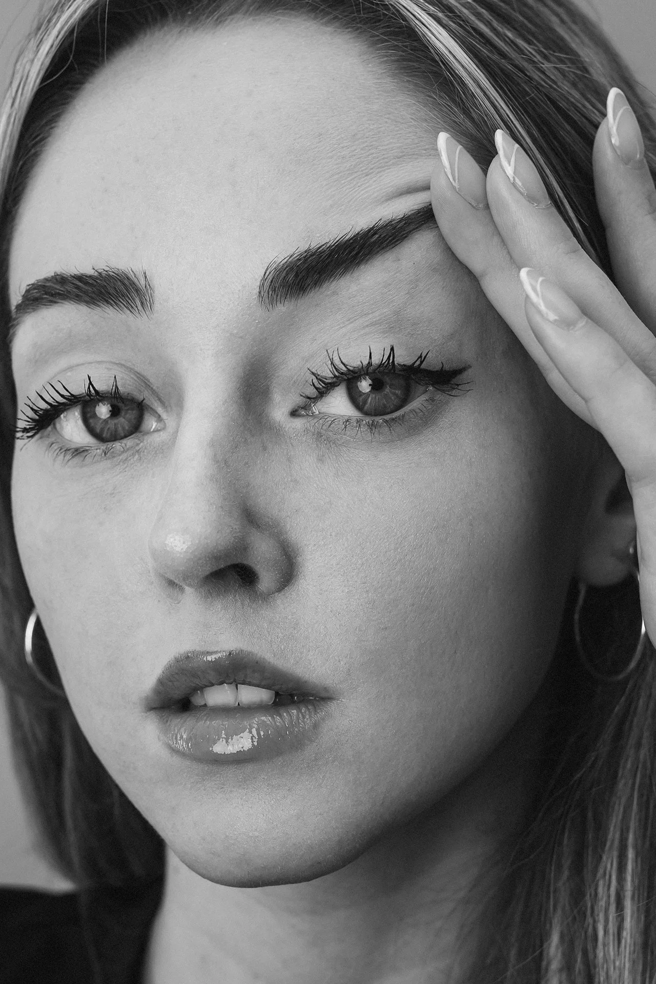 Ragazza con trucco leggero, sopracciglia disegnate, ciglia lunghe, e labbra lucide.