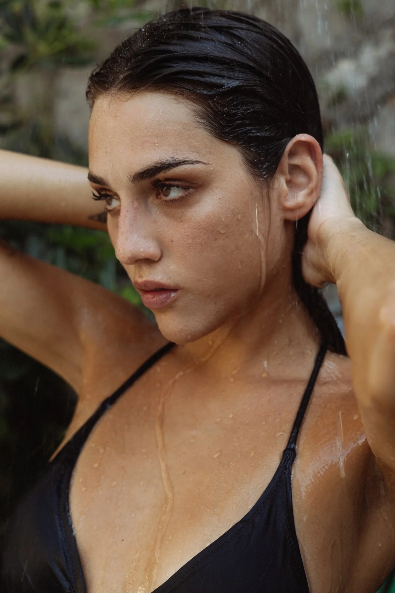 Ragazza con capelli bagnati e acqua che le scorre sulla pelle, sfondo naturale