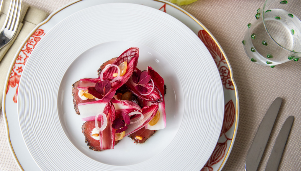 Thin slices of bluefin tuna carpaccio arranged on a plate with radicchio leaves.