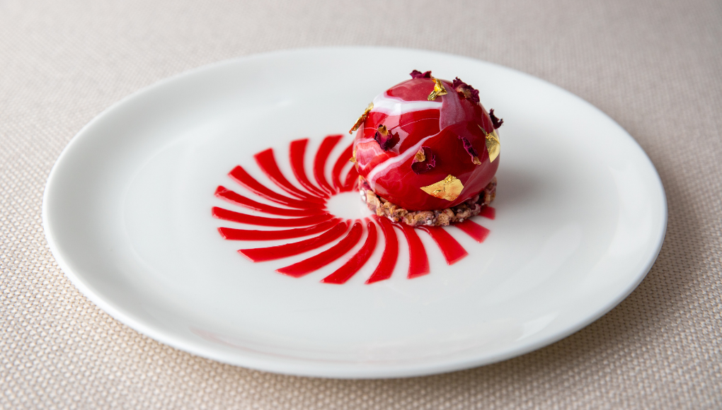 Individual raspberry and rose entremets with smooth glazed exterior, plated for dessert.