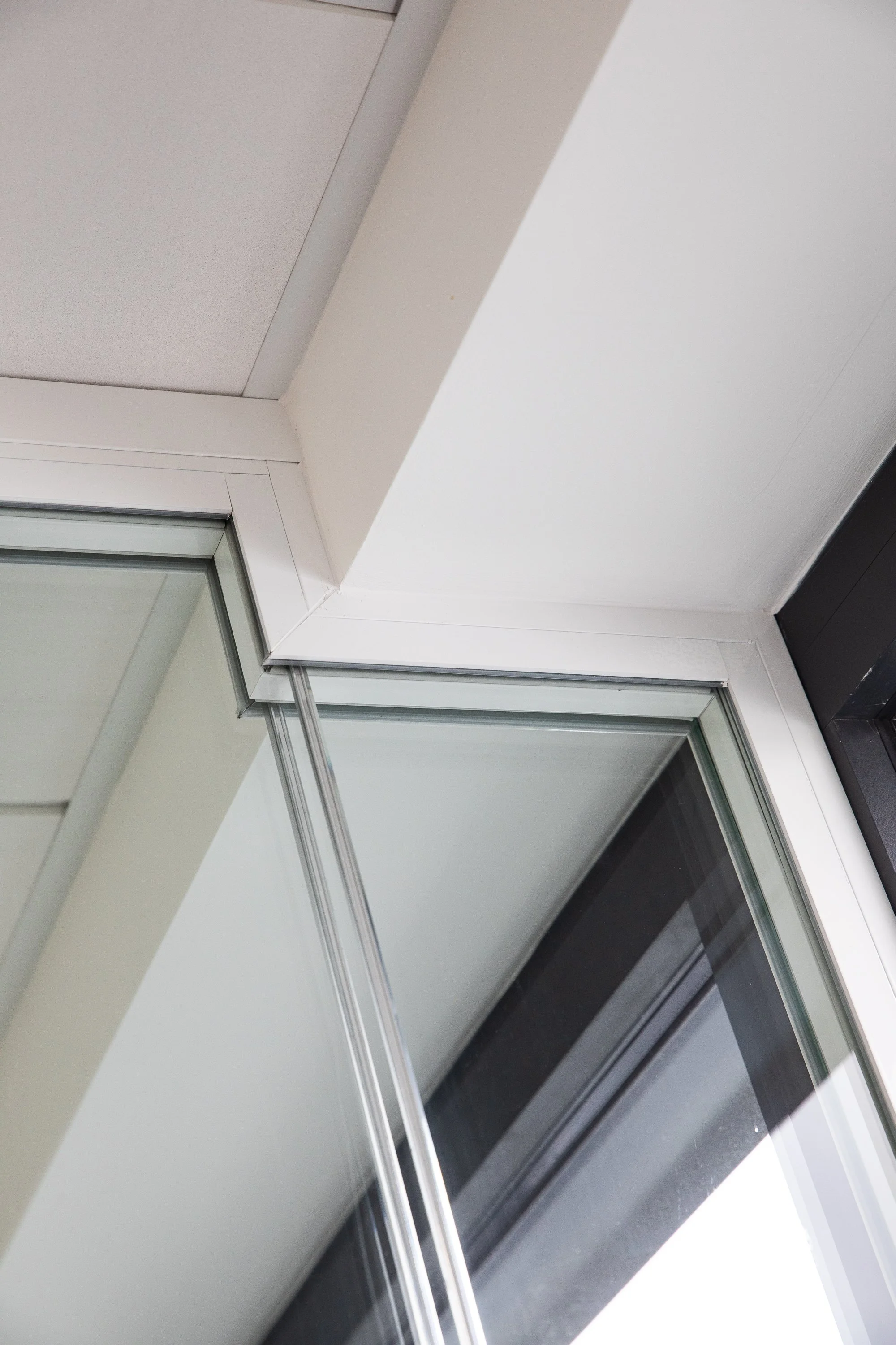 Close-up of a corner with a glass window and sliding door frame in a modern building.