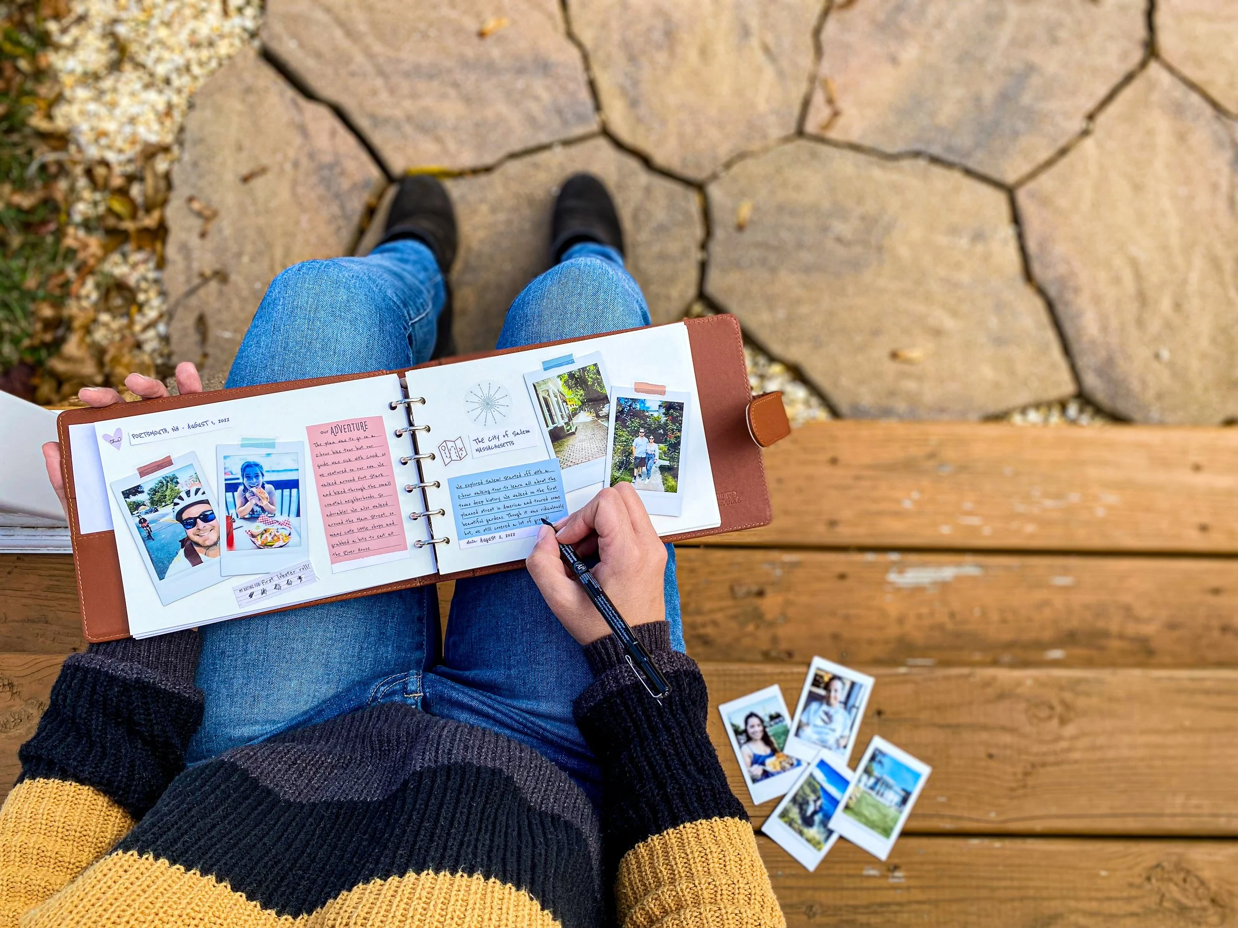 Women writing in her Capture Jounral that features photos of a trip and stickers.