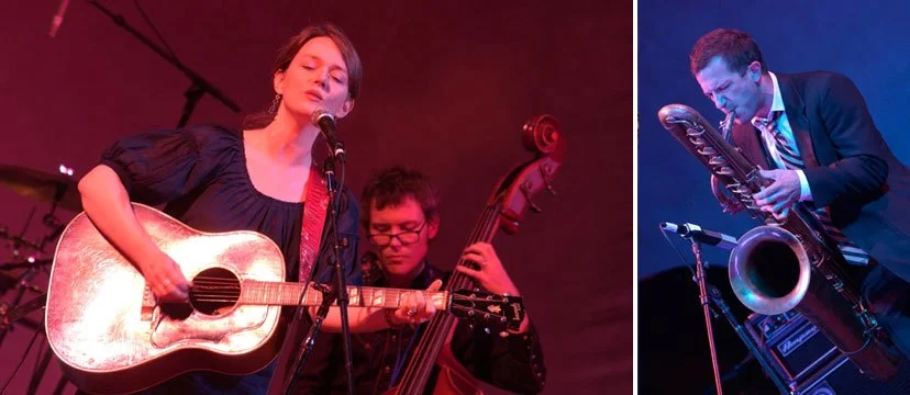 A female singer playing an acoustic guitar, accompanied by two male musicians playing a double bass and a saxophone, performing on stage.