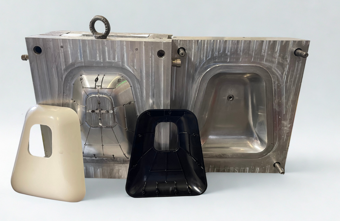 Une pièce métallique industrielle avec deux moules, un blanc et un noir, placés devant. Les moules semblent être destinés à la fabrication de pièces en plastique ou en autre matériau.