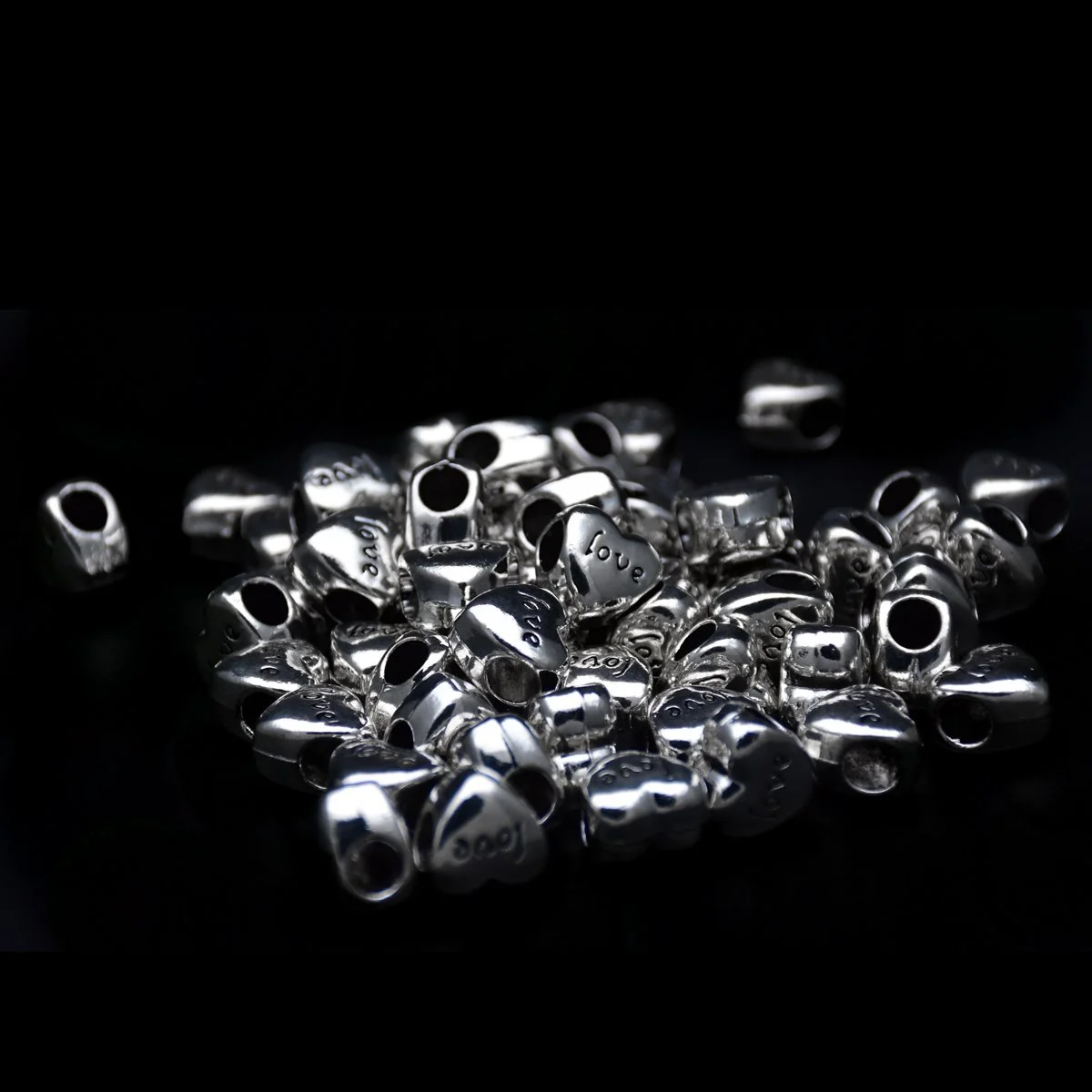 heart shape big hole pandora  jewelry beads with word love carved on the surface and seems scattering around in the black background