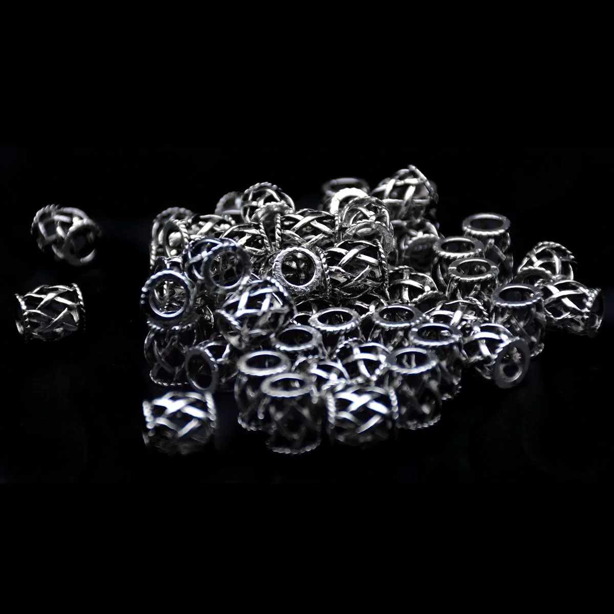 many of antique silver color big hole beads in twisted web shape scattering around in a black background