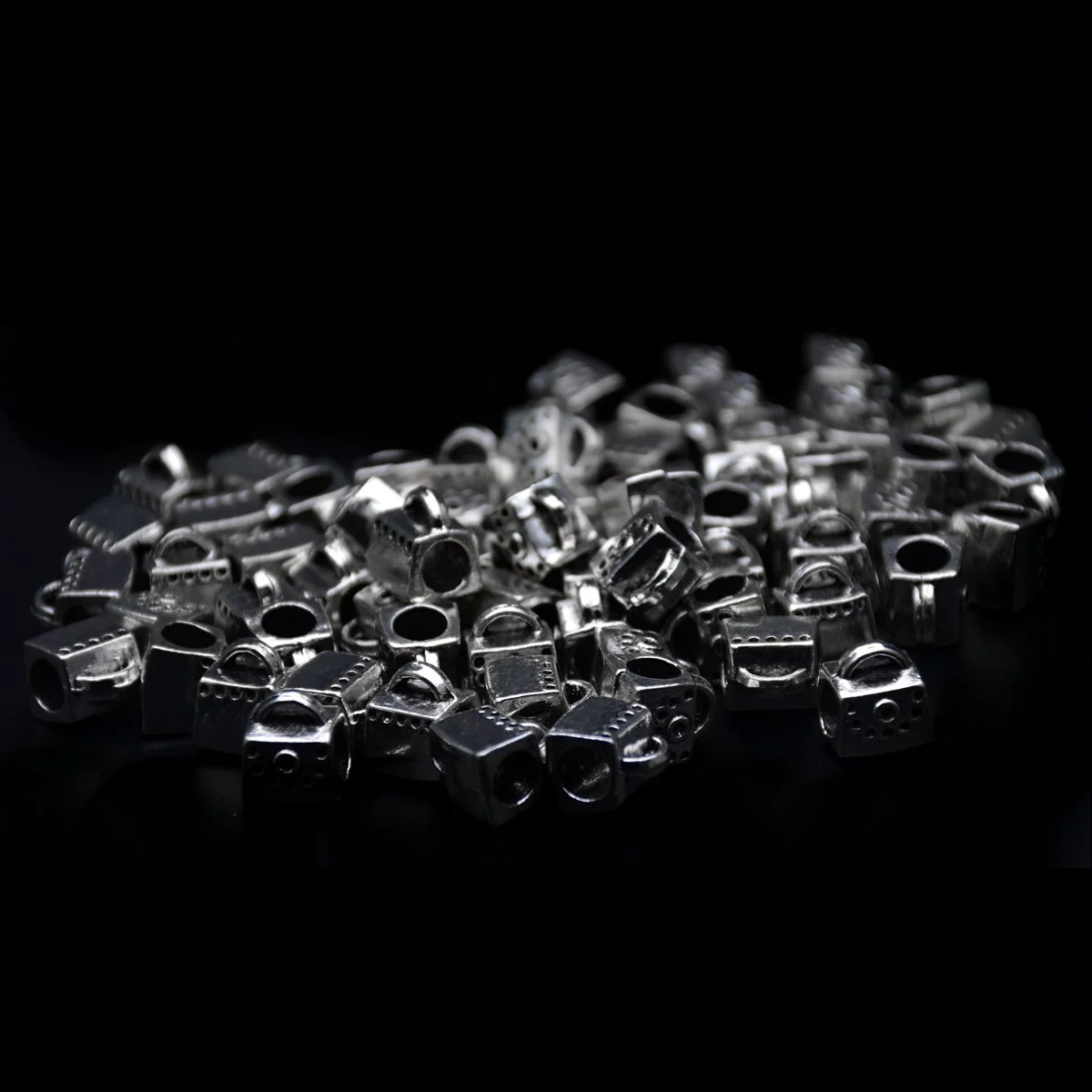 many of antique silver color handbag shape big hole pandora beads scattering around in a black background