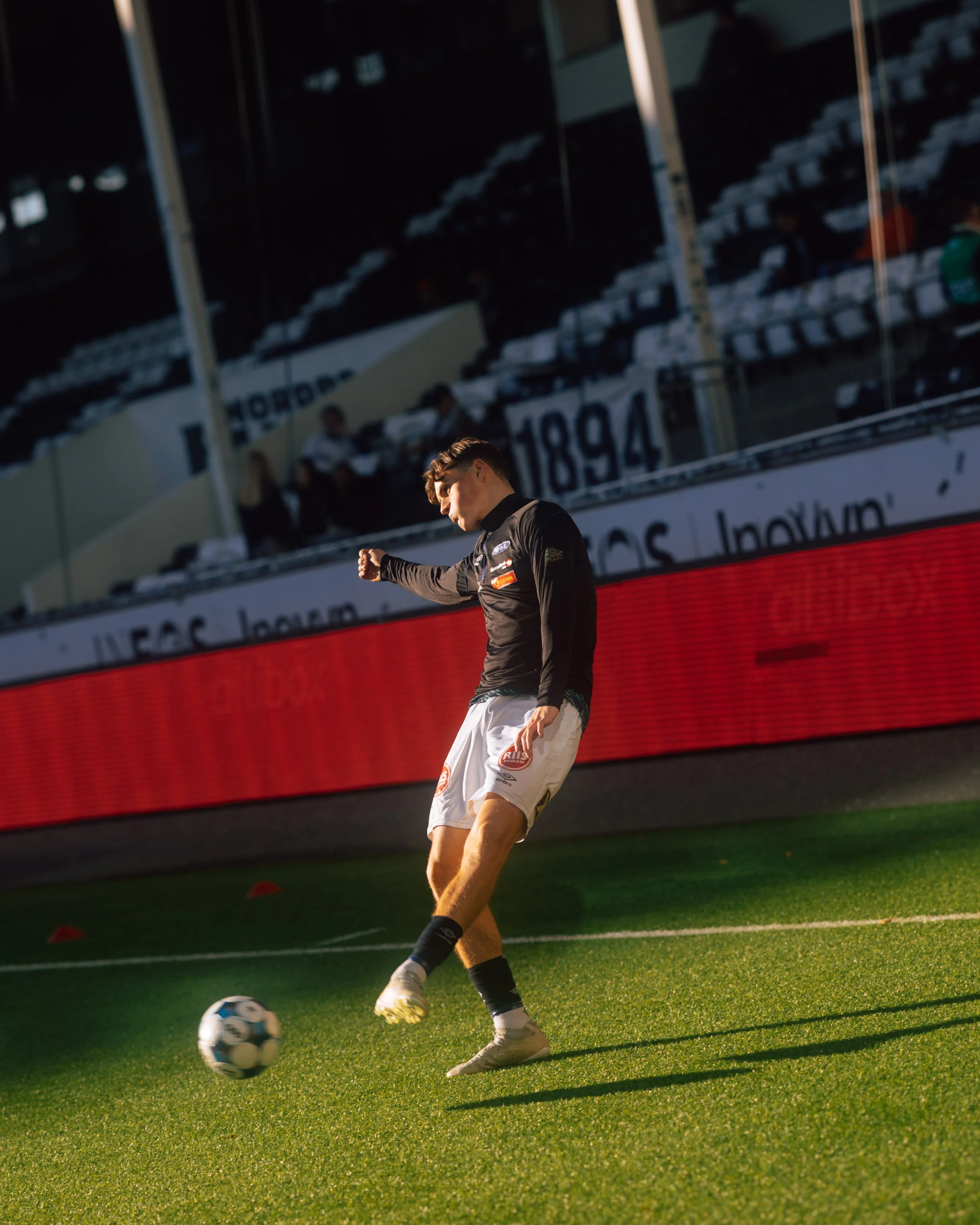 A male soccer player on the field about to kick a soccer ball.