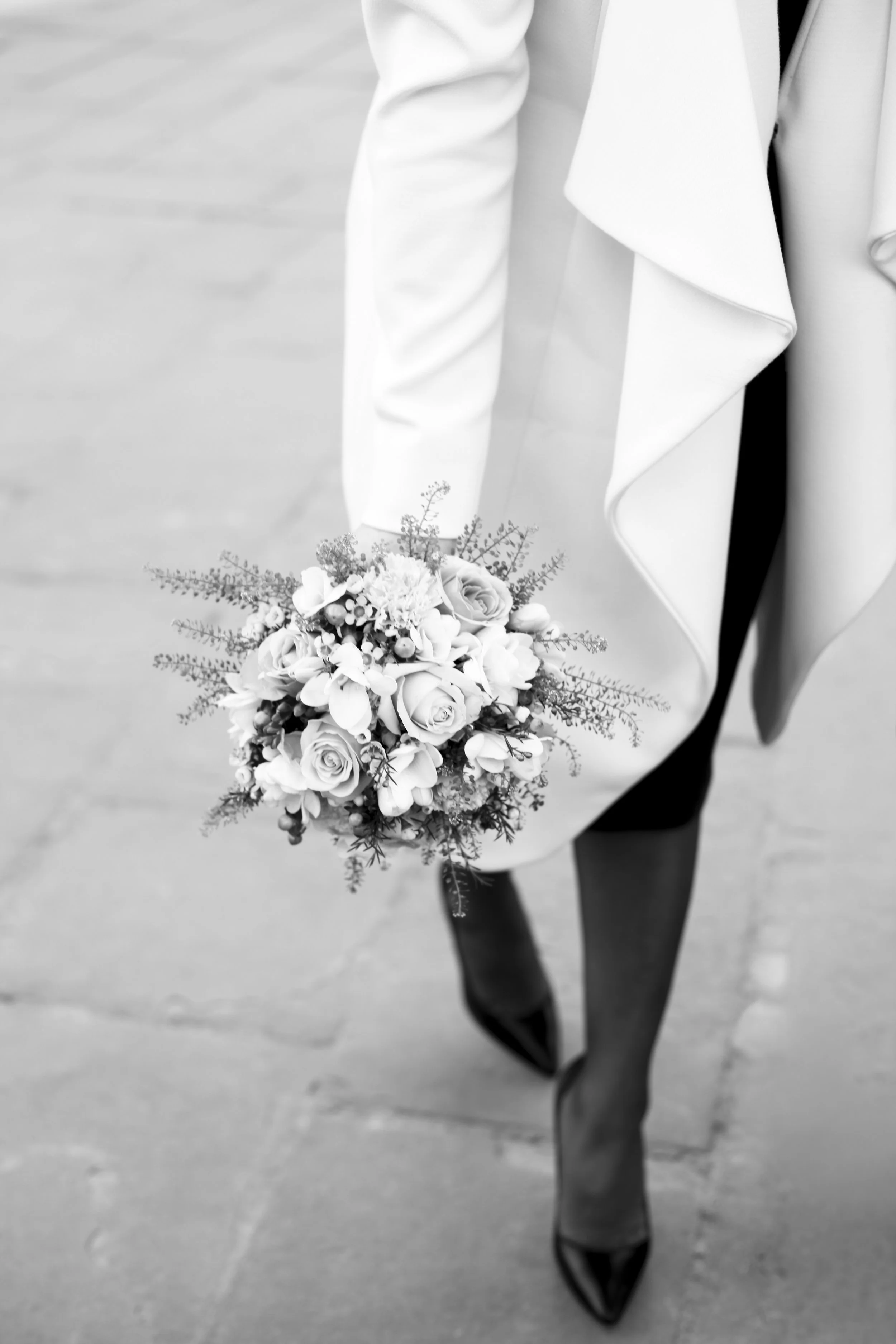 Black and white photo of a woman in a suit holding a bouquet of flowers