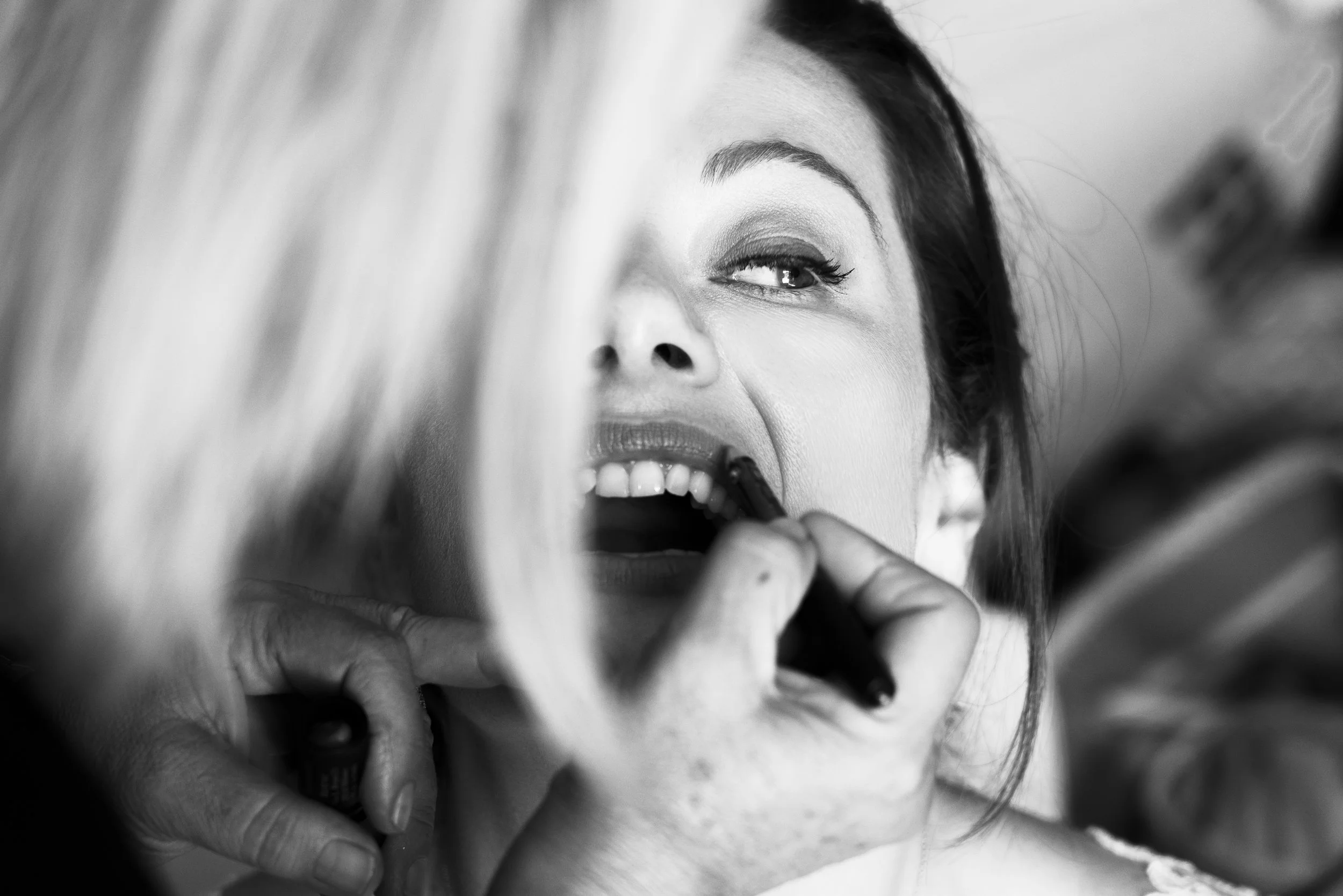 A woman getting her lips painted by a makeup artist.