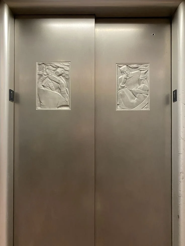 Metallene Aufzugstüren mit reliefartigen Figuren, die Menschen in Gespräche oder Interaktionen zeigen.