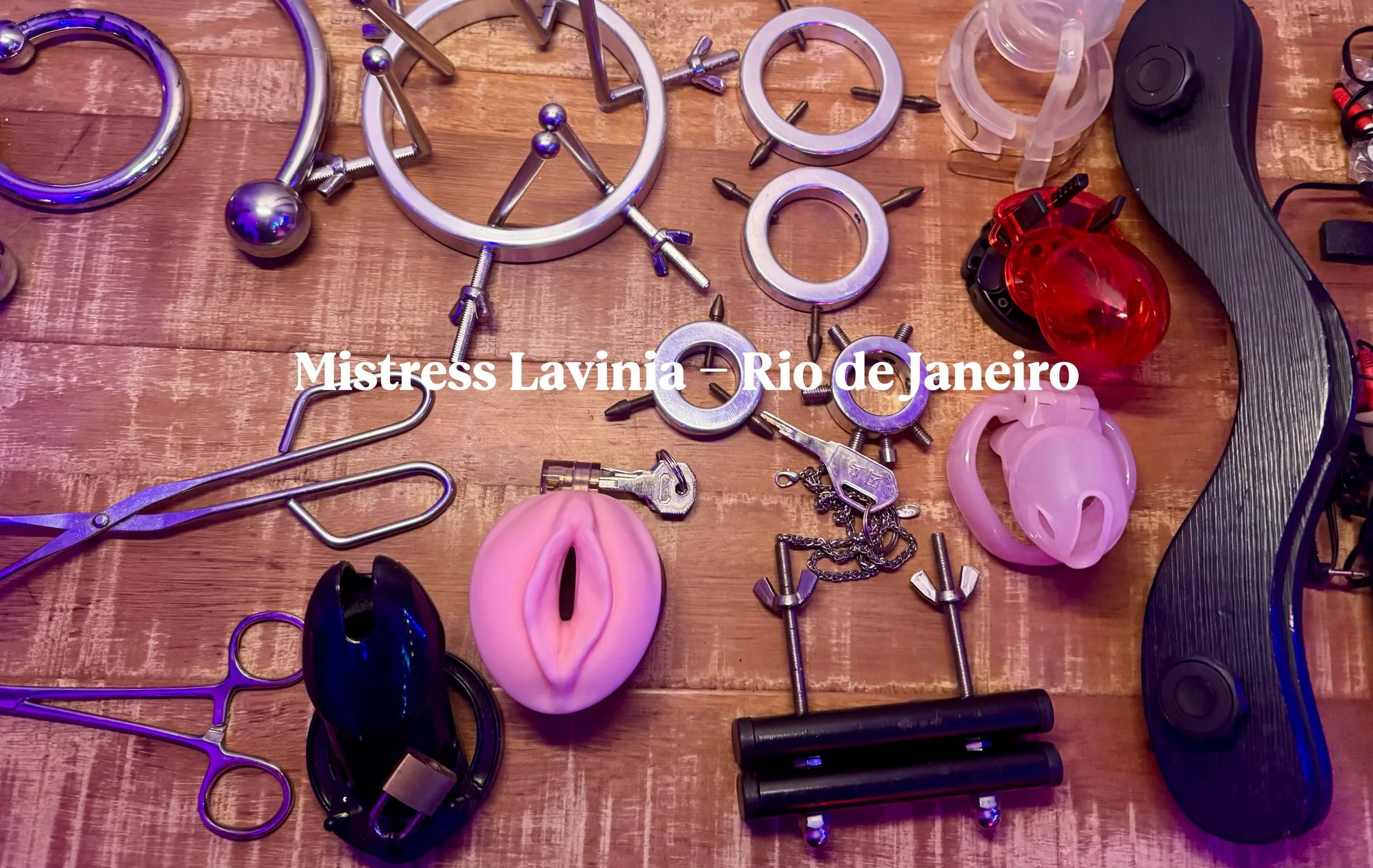 Coleção de acessórios eróticos e objetos de bondage em uma mesa de madeira, incluindo algemas, chicotes, plugues de metal, correntes e outros brinquedos adultos, com uma legenda em português: "Mistress Lavinia - Rio de Janeiro."