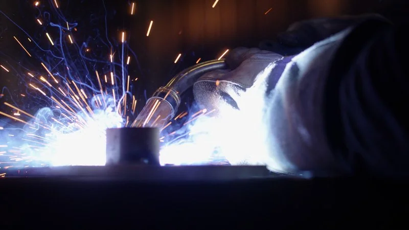 En person som svetsar med ljusblixt och gnistor som sprutar.