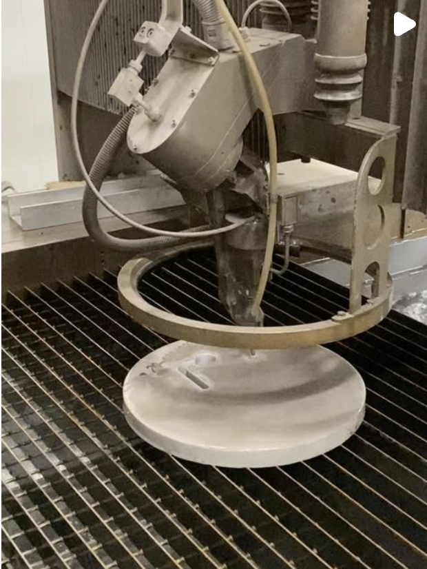 En industriell maskin som omformas, med ett roterande verktyg, placerat över ett metallgaller.