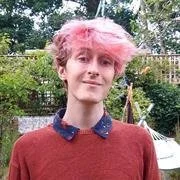 Person with pink hair smiling outdoors