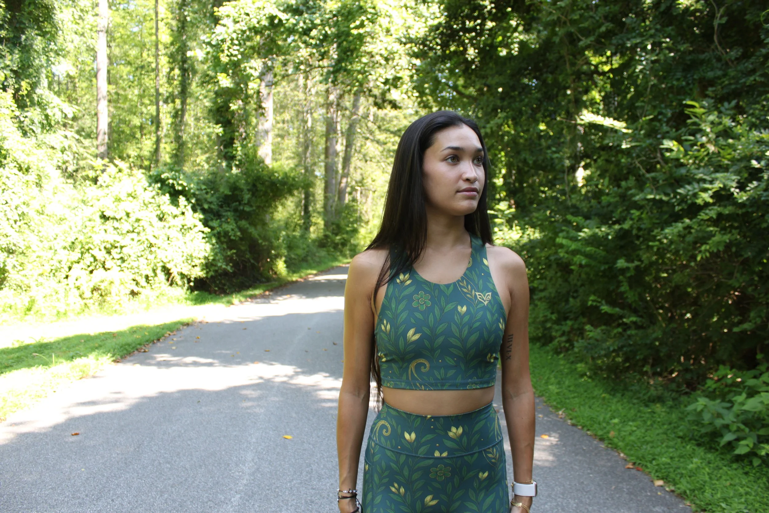 Woman wearing an Eryvalen green floral running set on a wooded trail.