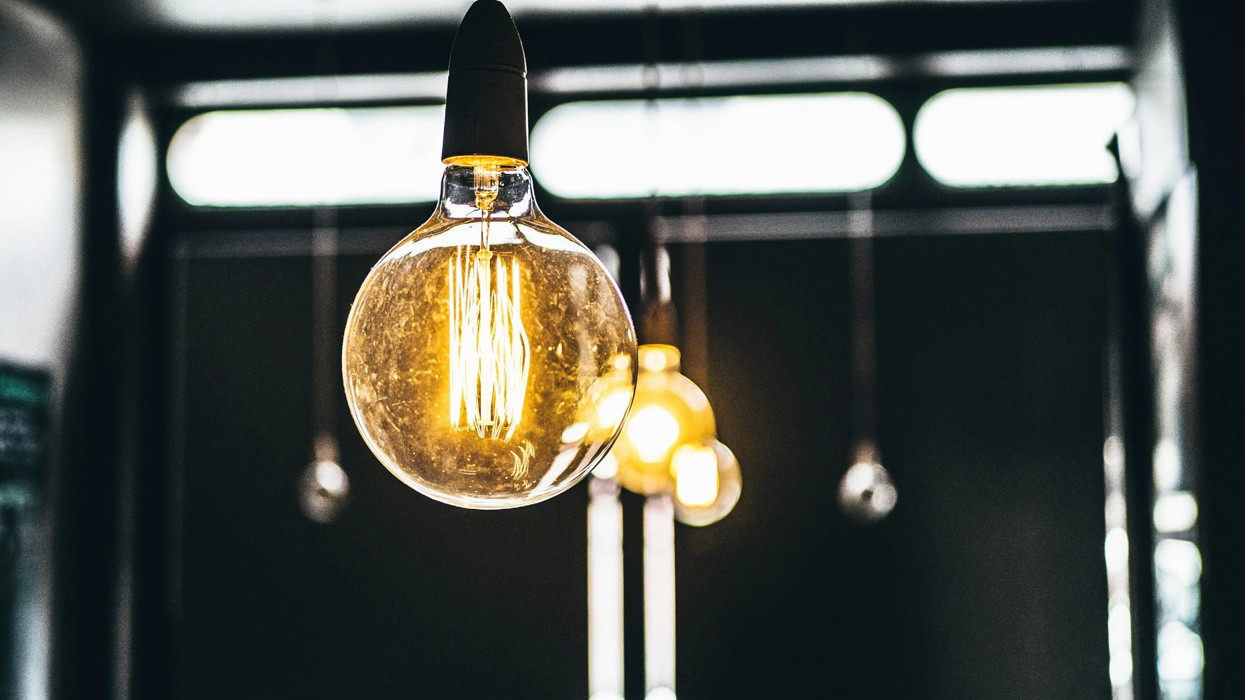 Close-up of illuminated vintage-style Edison light bulbs hanging from the ceiling in a dimly lit room.